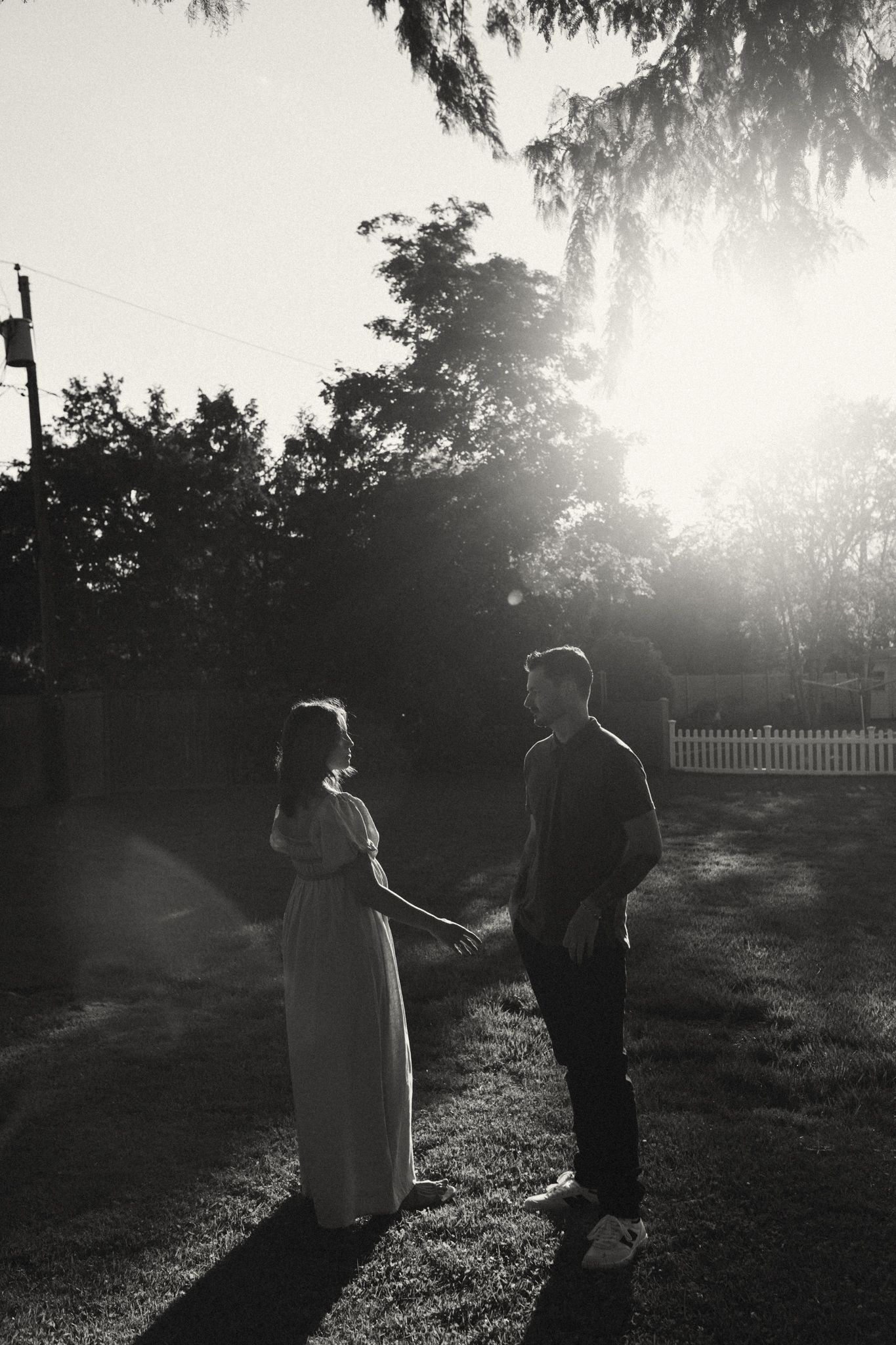 A black and white photo series capturing a couple's intimate moments in a sunlit garden.