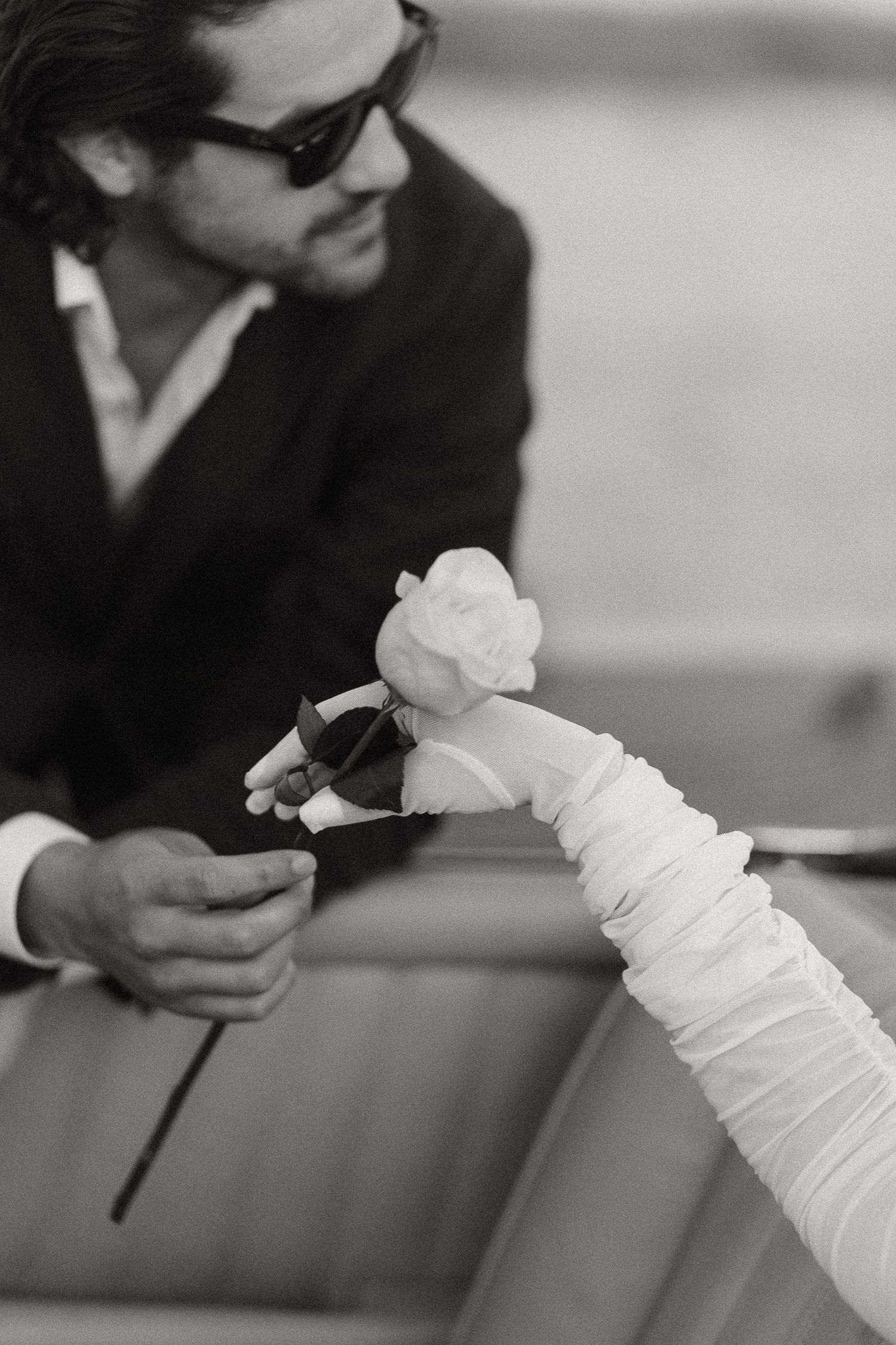 Black and white photo of hands holding white fabric against a blurred background.
