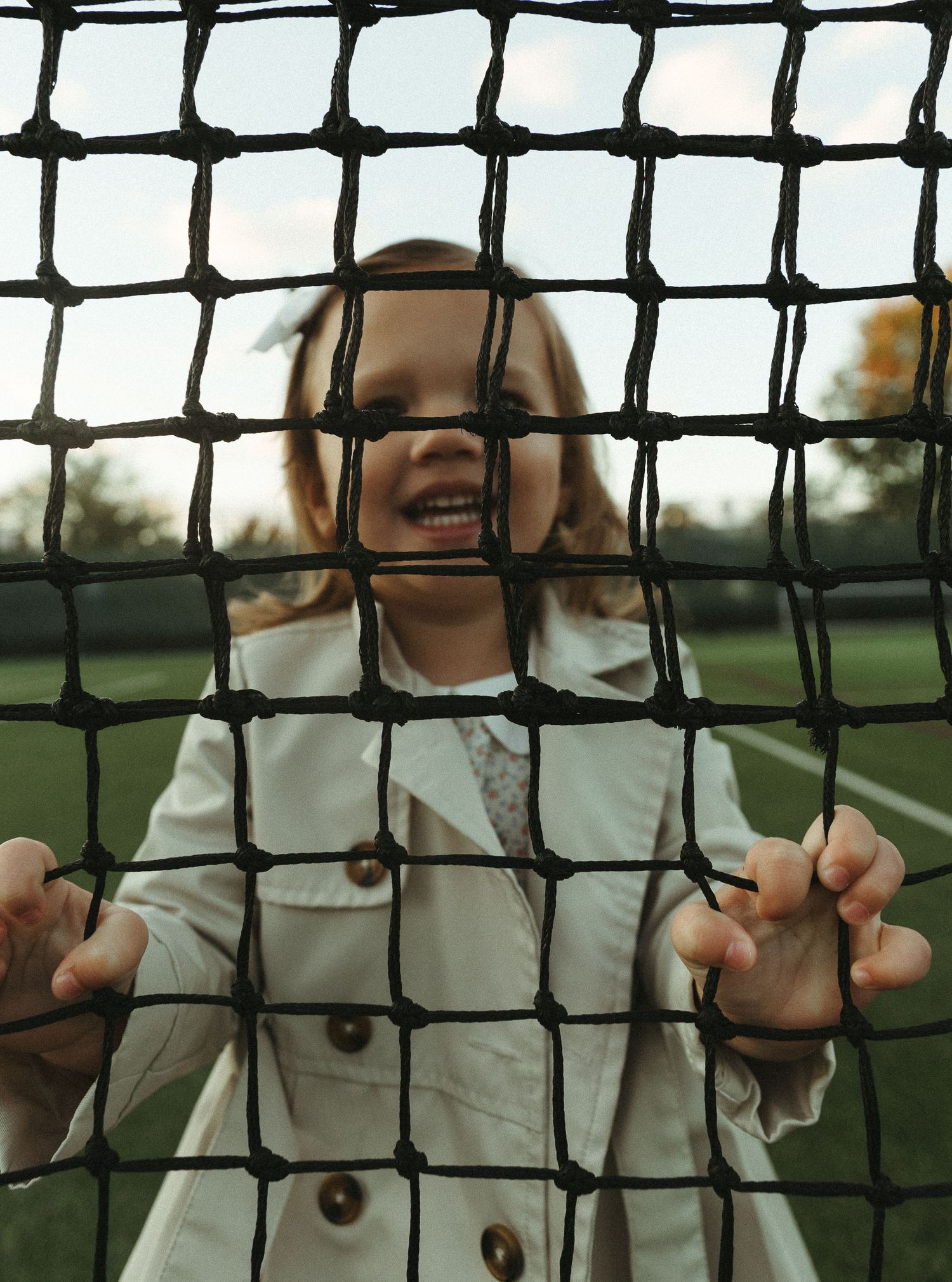 View through tennis court net mesh during golden hour.