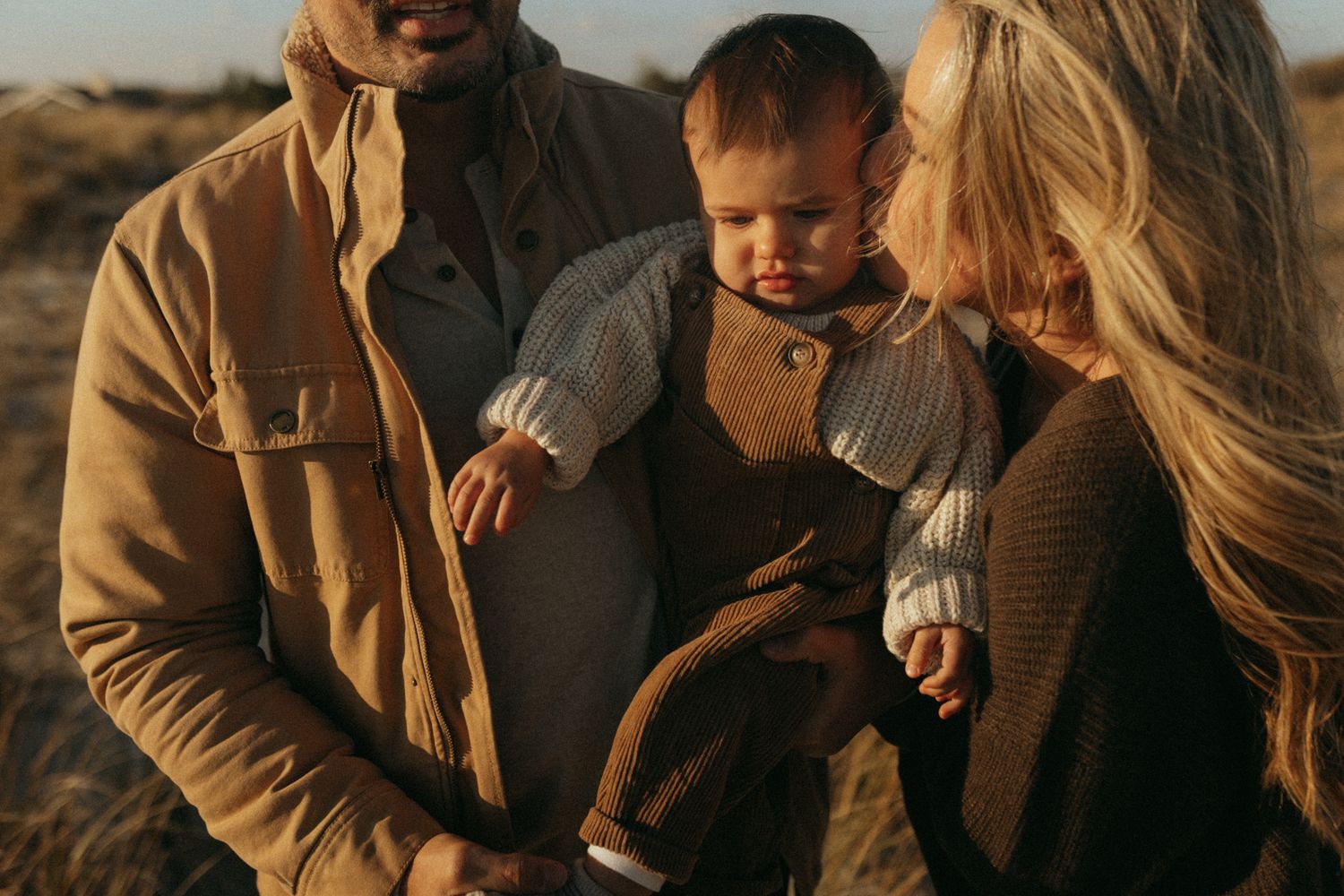 A cozy outdoor gathering with warm sweaters and autumn tones at sunset.