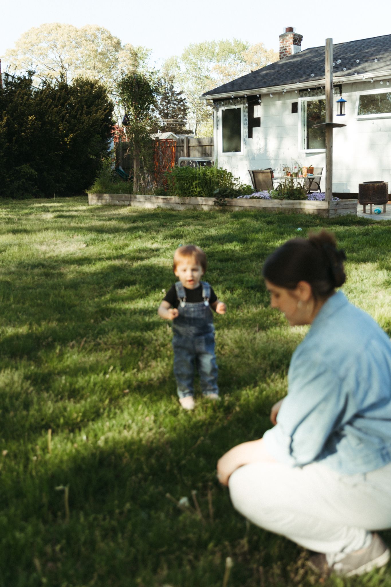 A sunny backyard scene with a small house and people enjoying the outdoors.