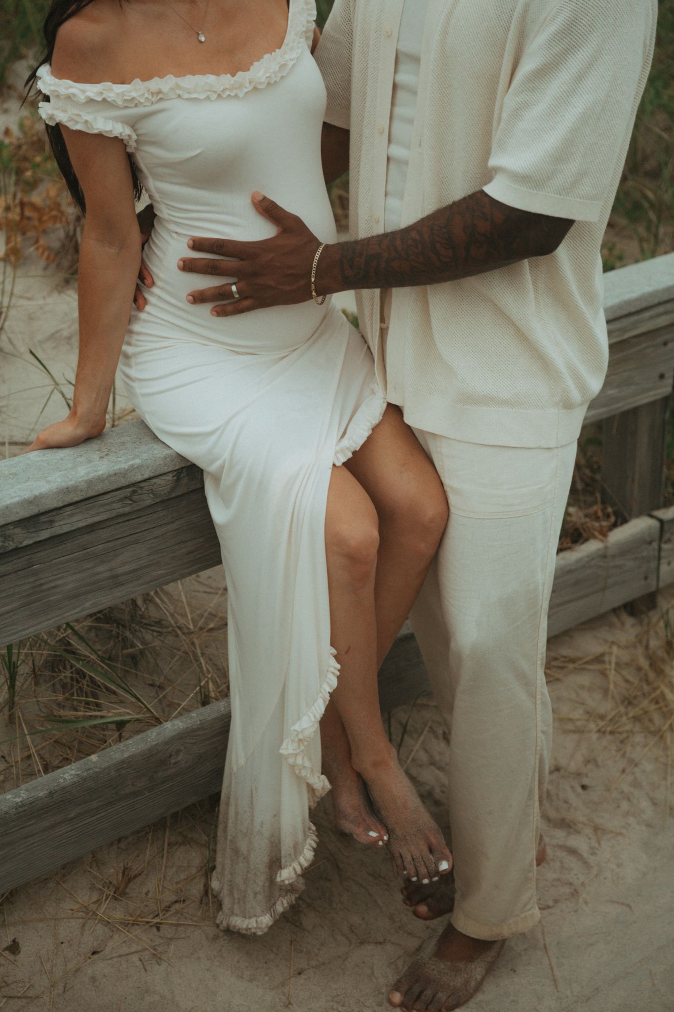 Close-up of couple sitting together on wooden beach walkway.