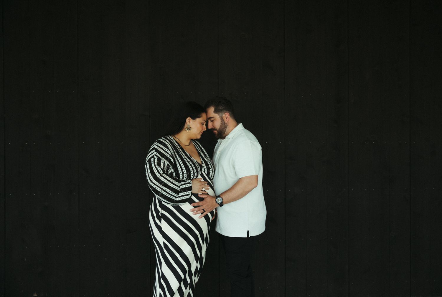 Two people embracing in dramatic lighting against a dark background.