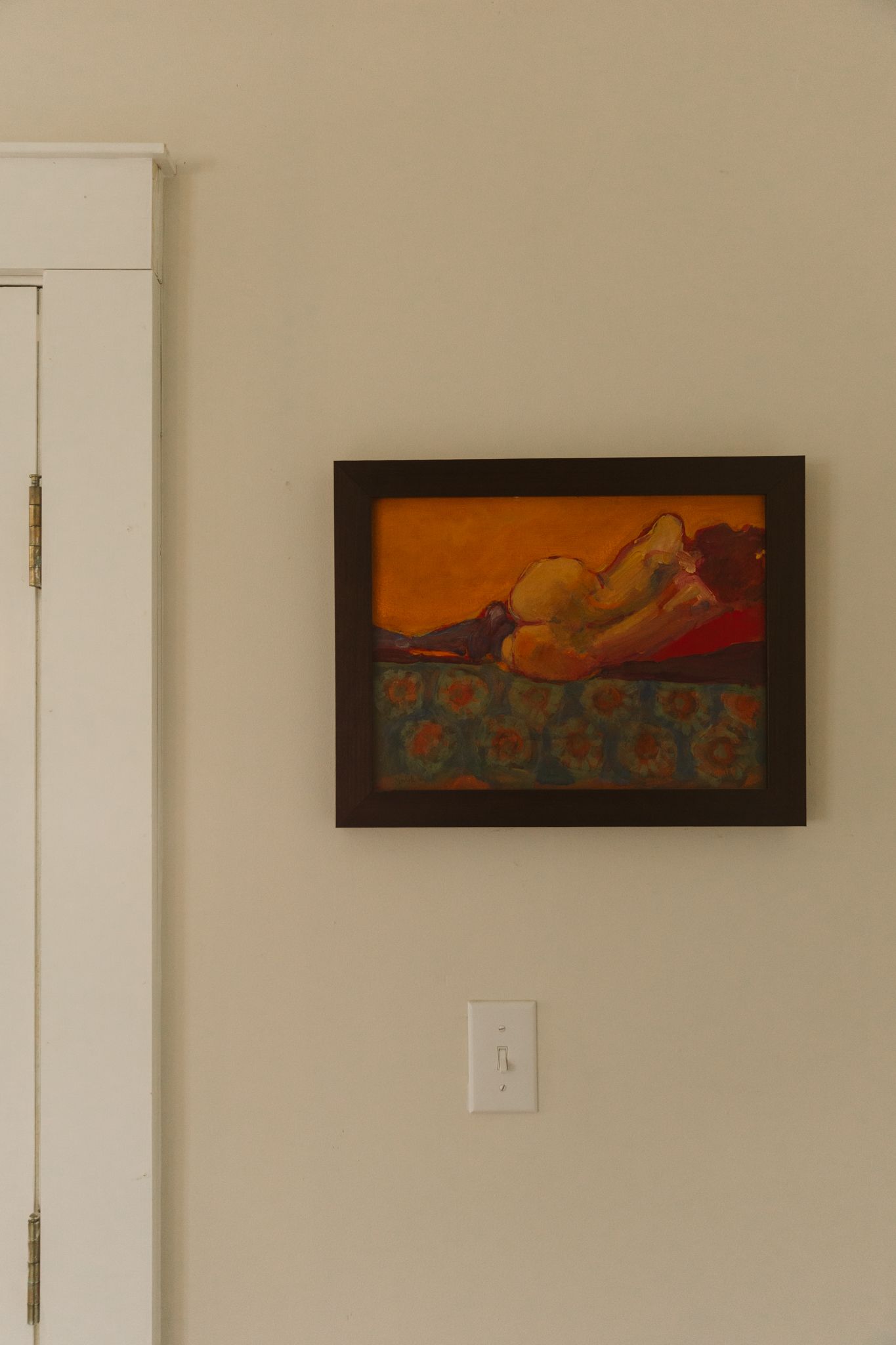 Orange-toned artwork displayed in frames on a beige wall.