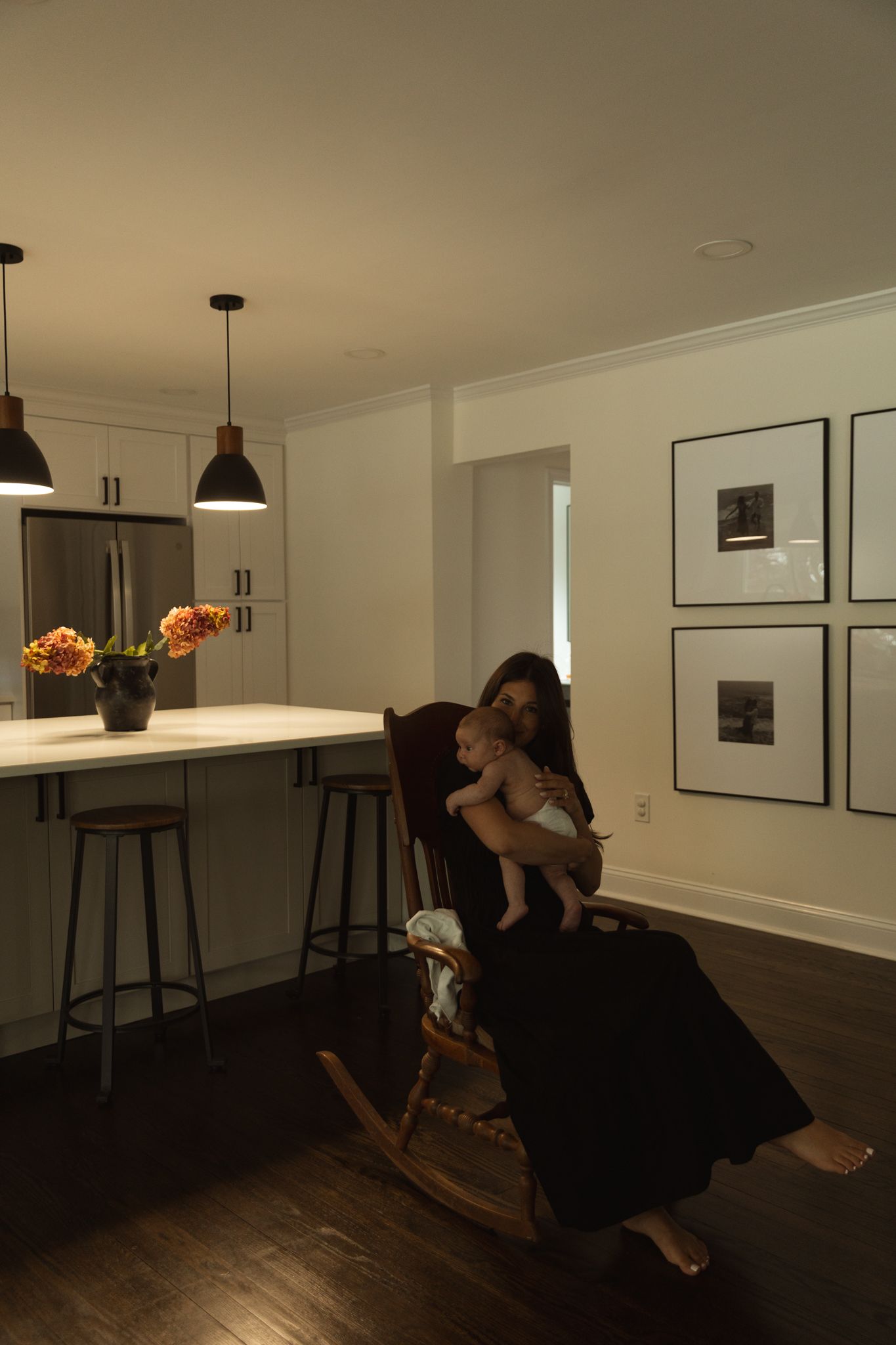 A moody interior scene with a black dress against dark hardwood floors and white walls.