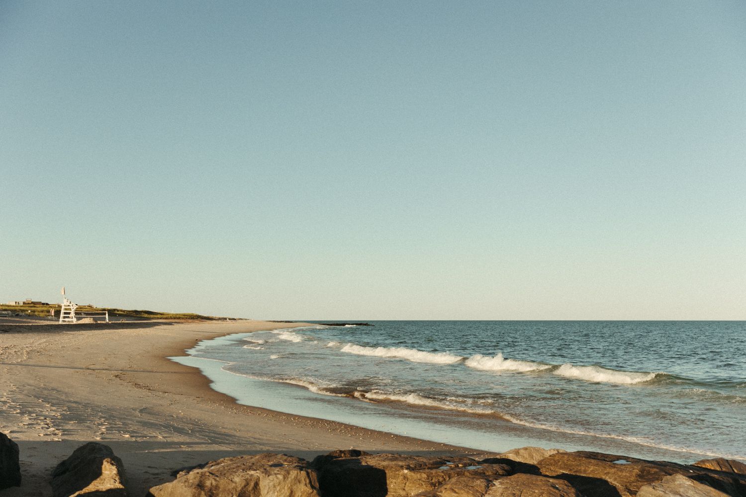 Scenic beach landscape with waves crashing on the shore during sunset.