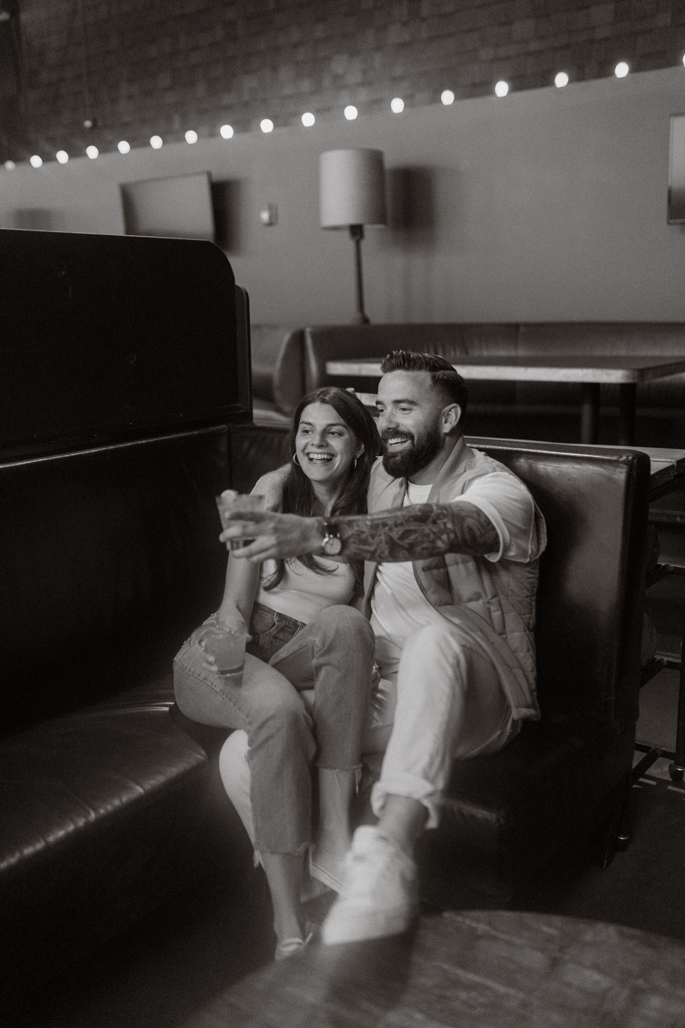 Black and white photos of a couple laughing and relaxing on a leather couch.