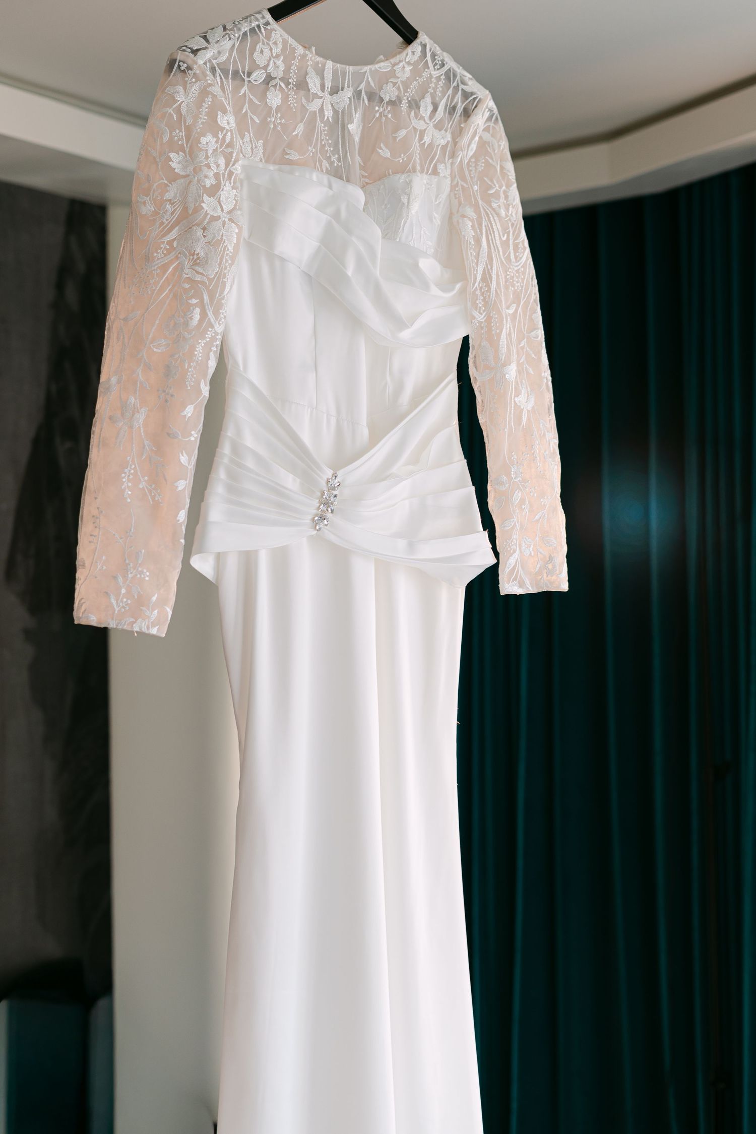 Elegant long-sleeve lace and satin wedding dress hanging on display.