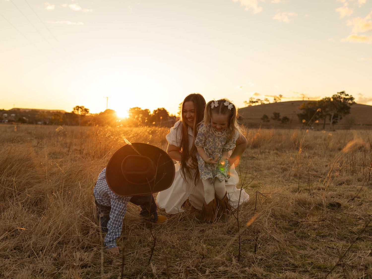 Mother and two young children planting in a golden sunset field on a rural Australian farm.