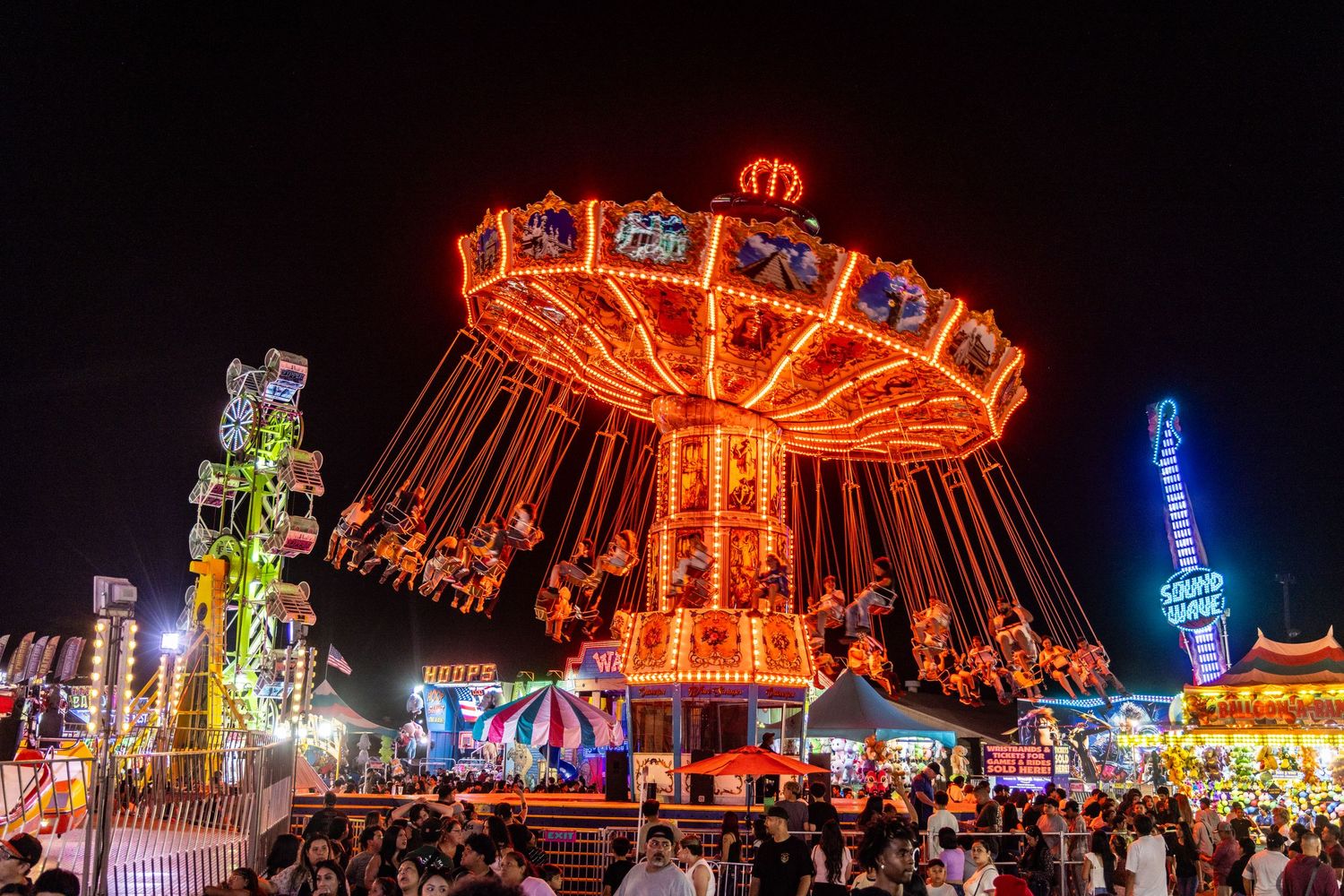 Illuminated chain swing carousel ride at a county fair at night.