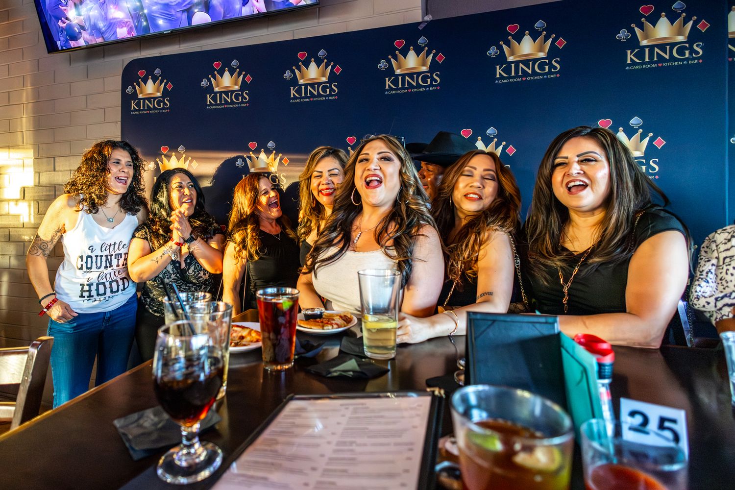 Group of women laughing and celebrating at Kings bar, enjoying drinks together at a lively bachelorette party.