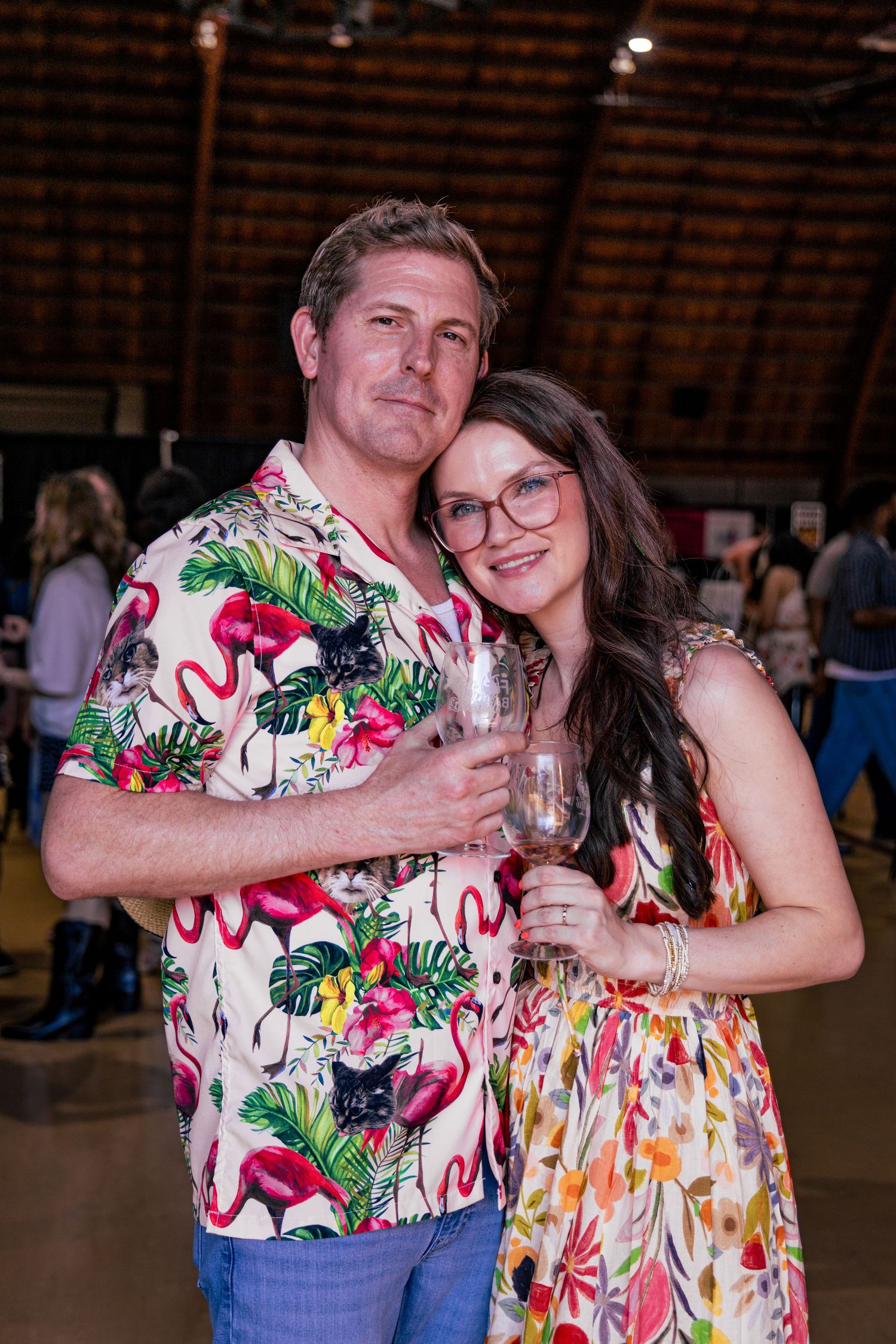 Couple posing together at a wine event, man in flamingo shirt holding wine glass with partner.