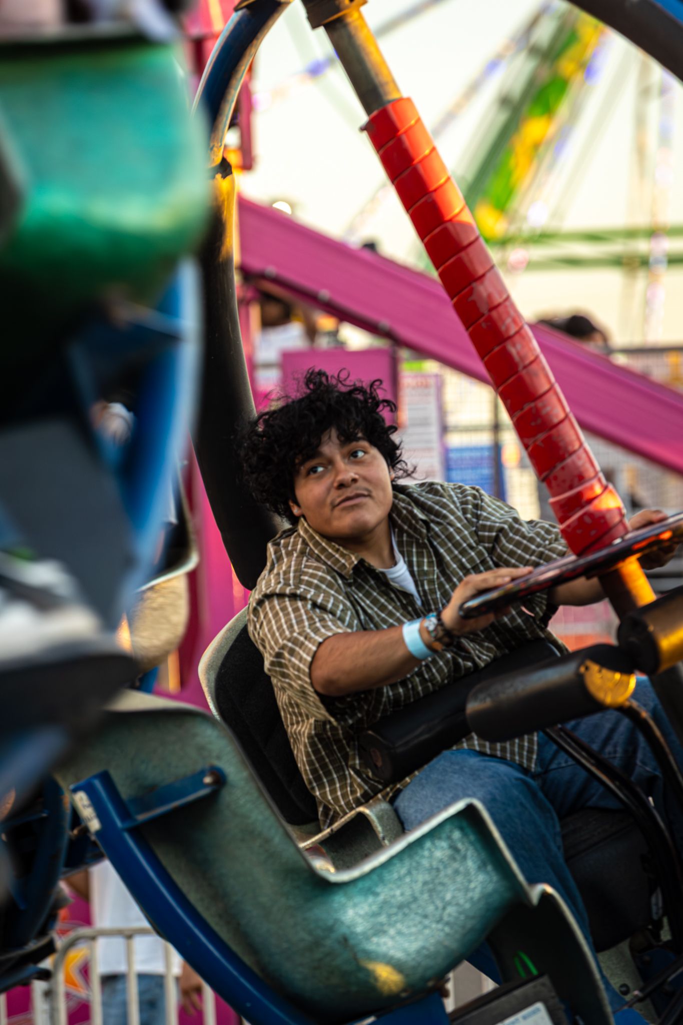 Young man enjoys a carnival ride at a county fair surrounded by colorful attractions.