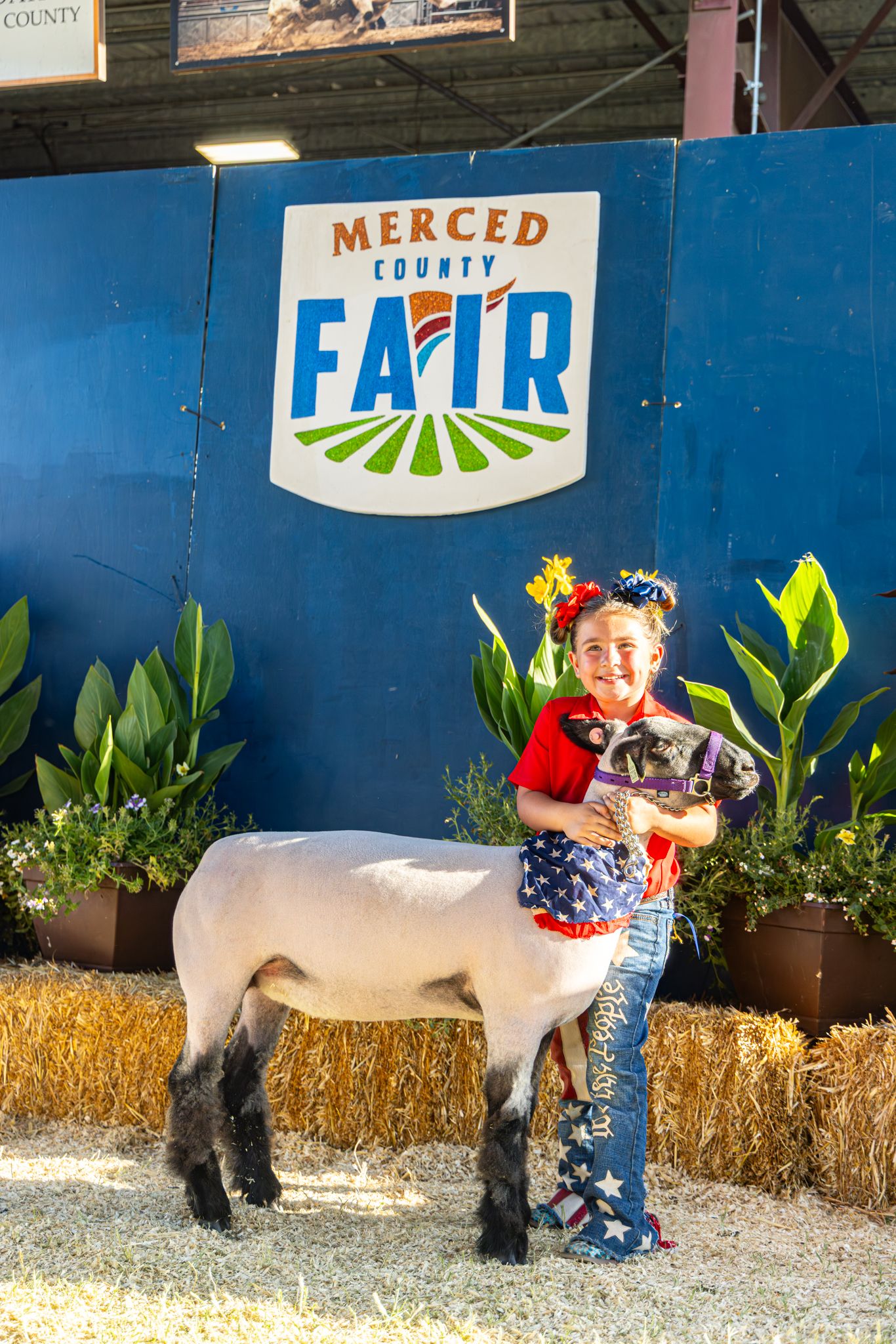 Young girl proudly poses with her show lamb at the Merced County Fair.