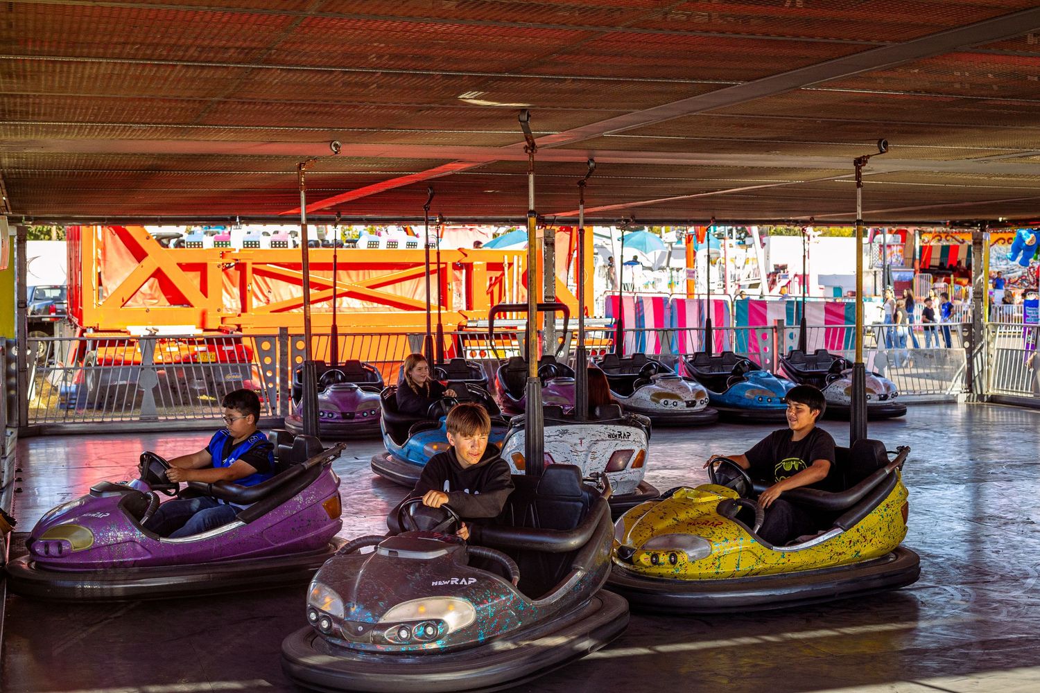 Children riding colorful bumper cars at a fun carnival amusement park ride attraction.
