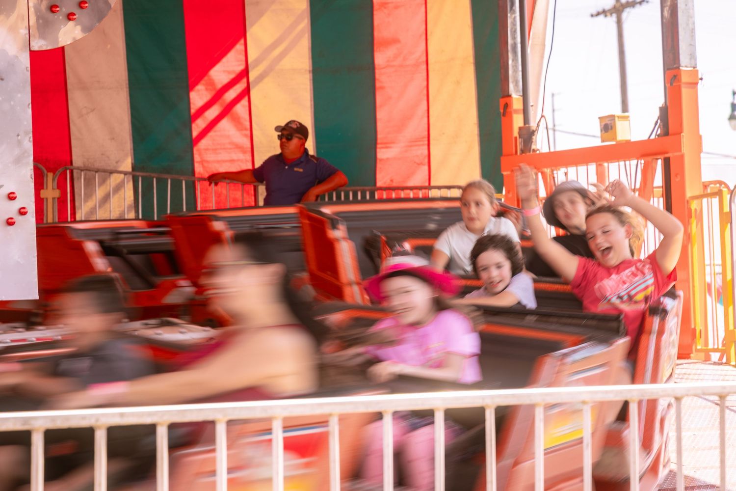 Excited children riding a spinning fair ride with motion blur at an amusement park.