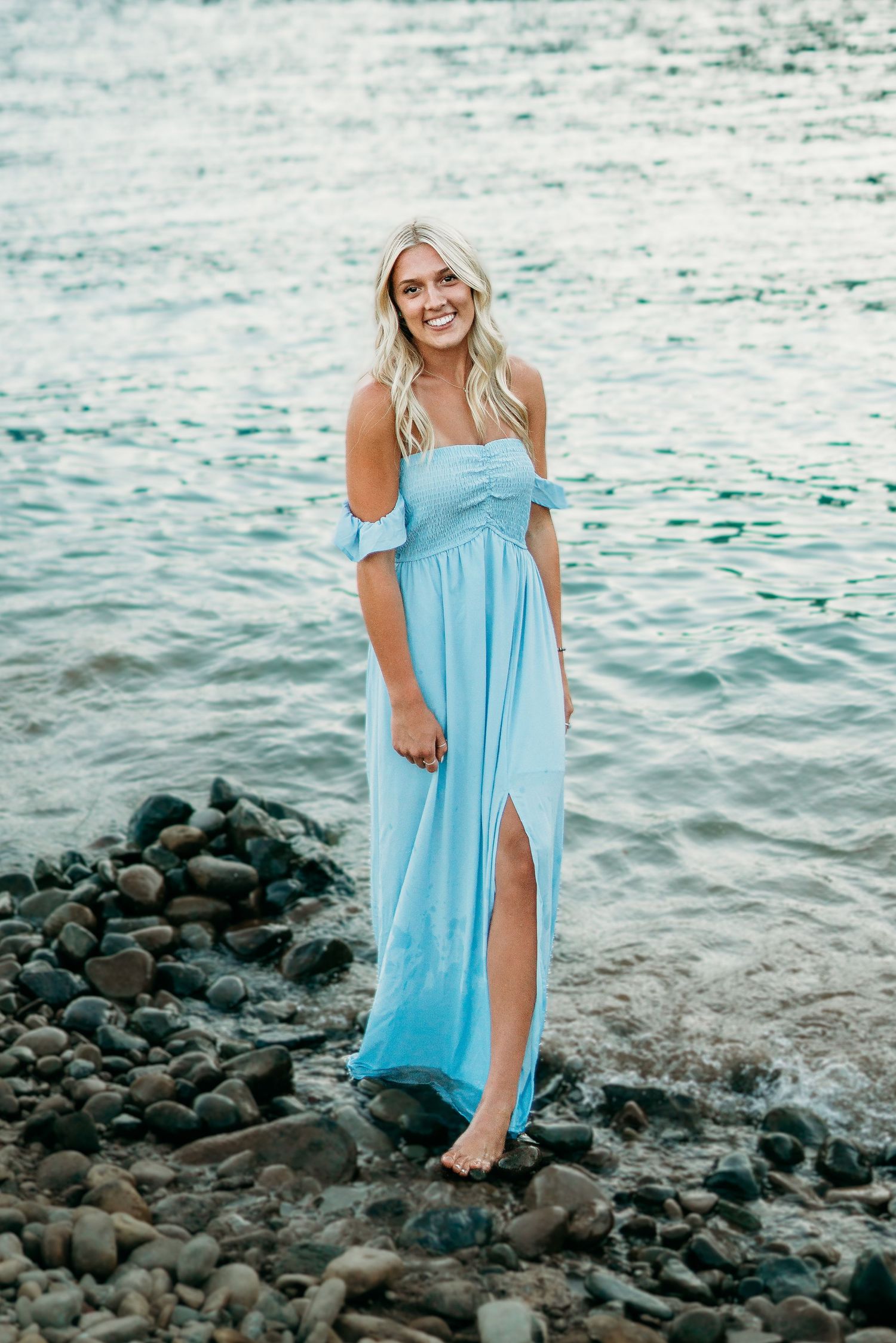 Senior girl standing in water and rocks with a flowing dress