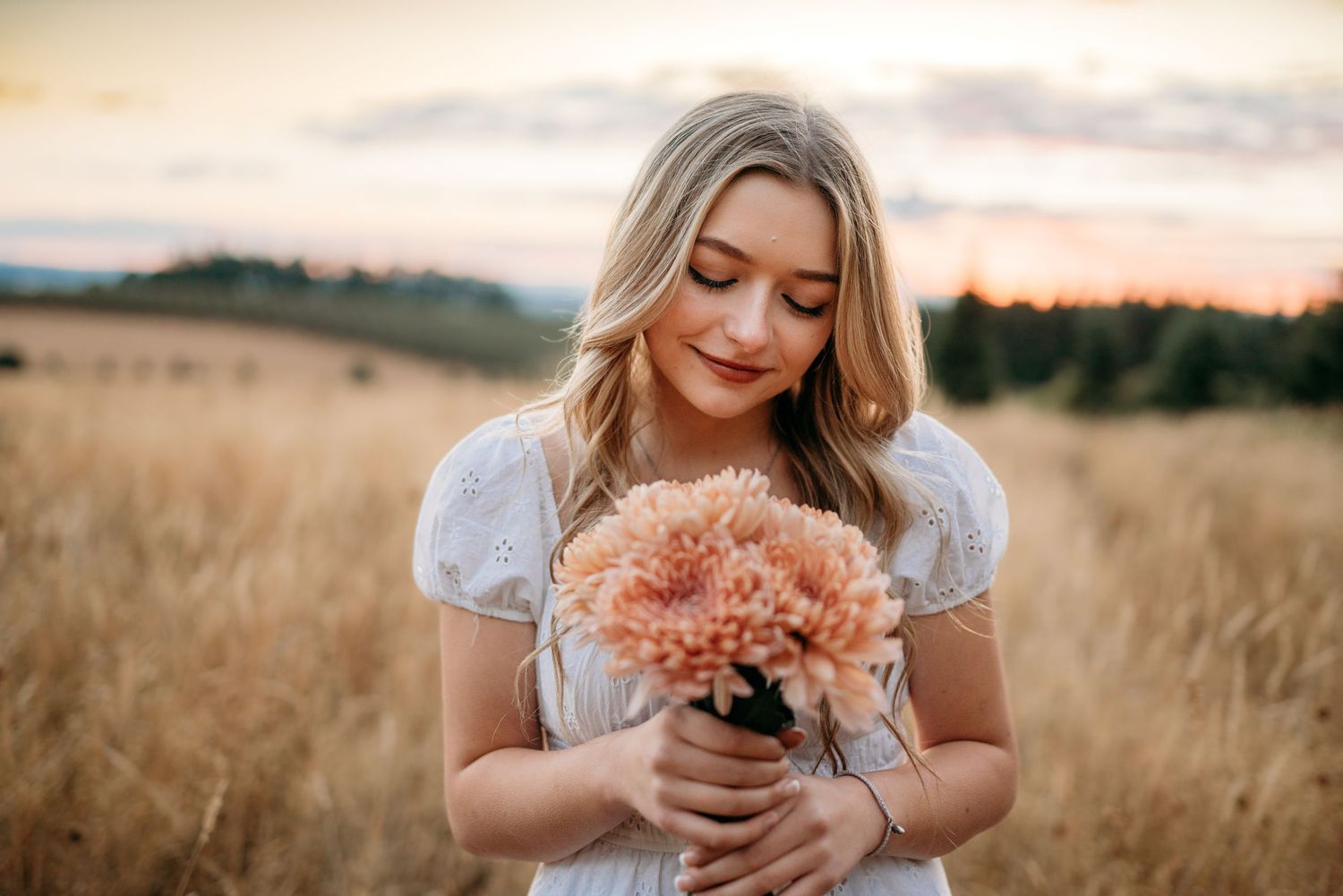 Senior girl holding flowers in a field at golden hour