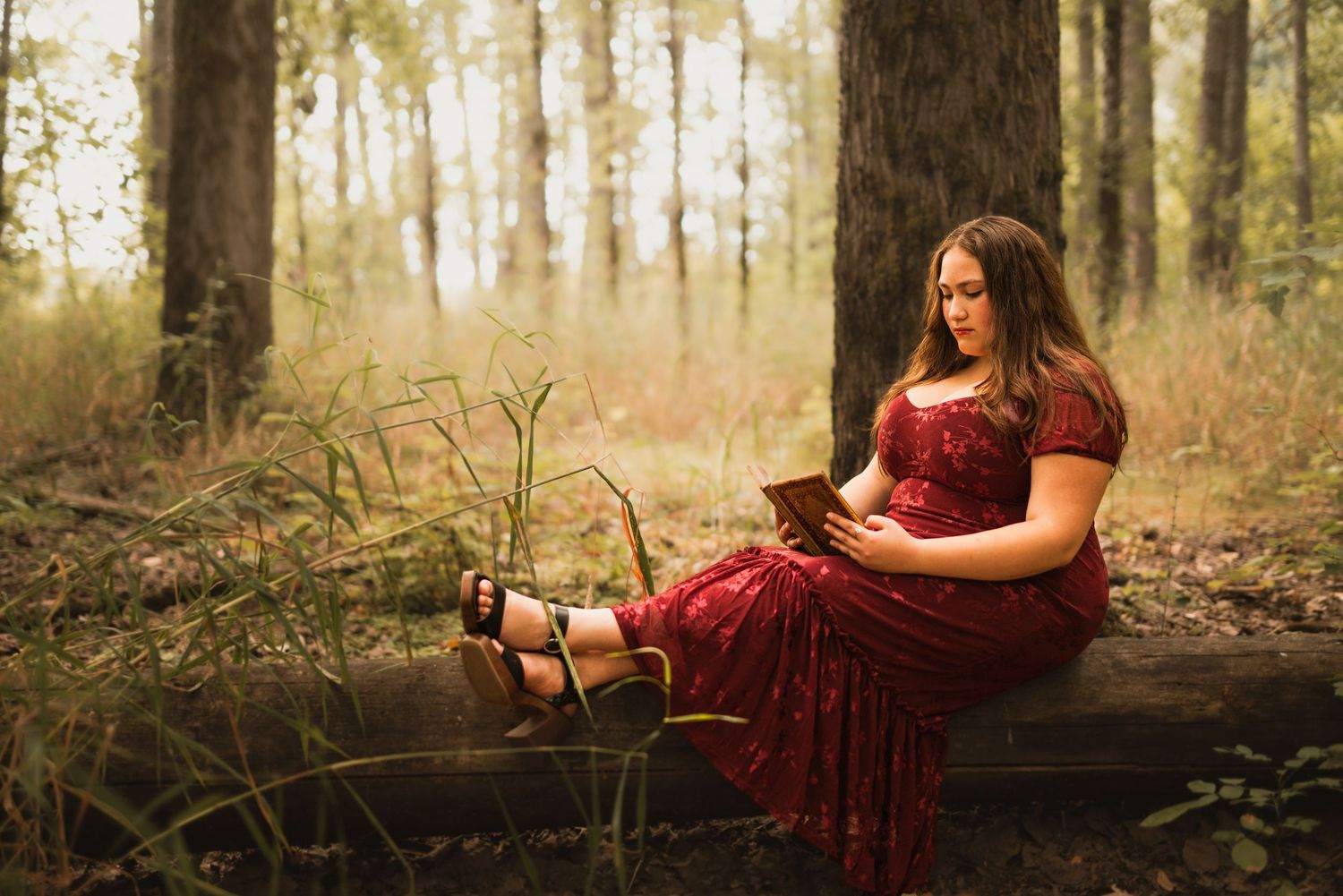 Senior girl sitting in the woods wearing a flowing dress