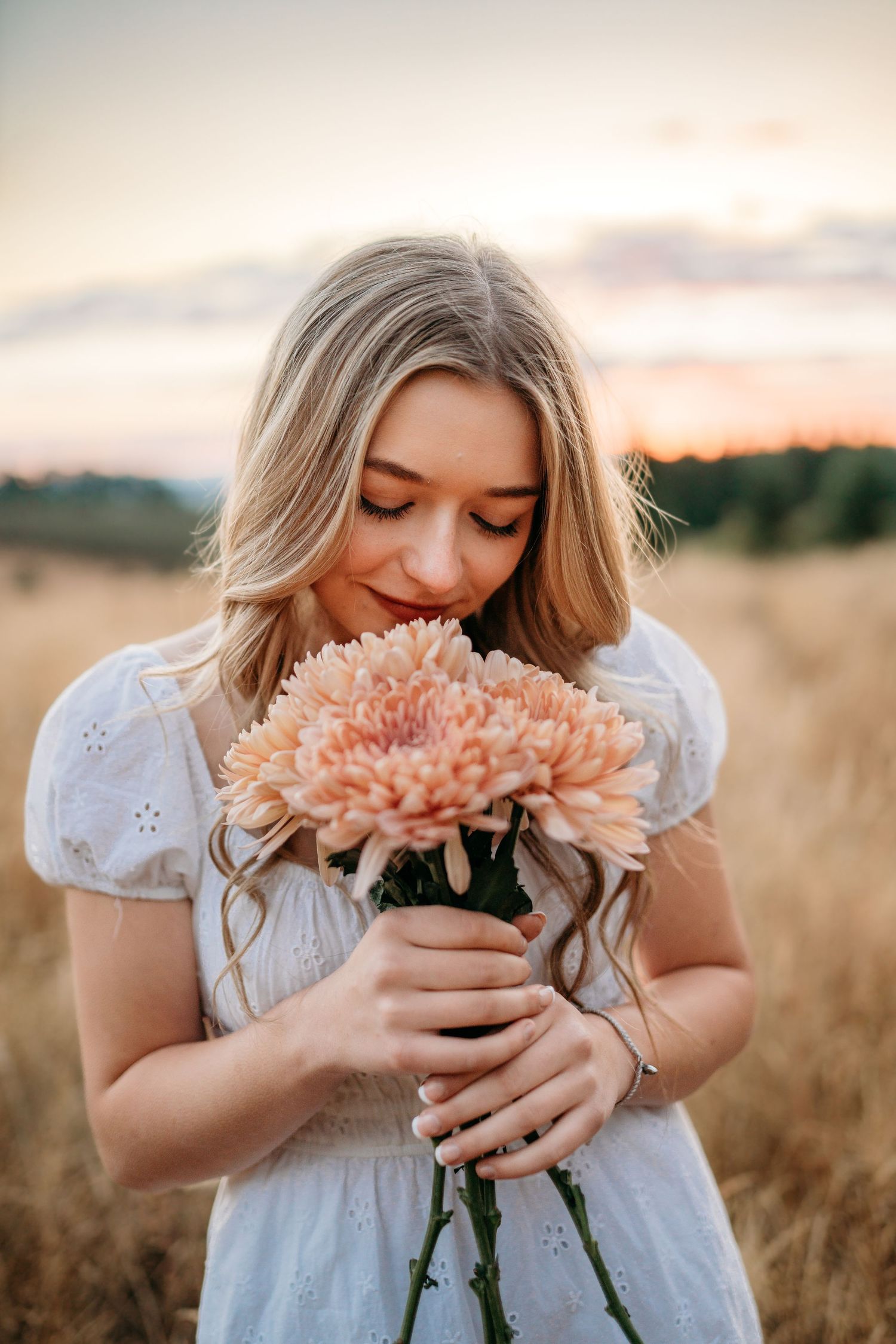 Senior girl smelling flowers at golden hour