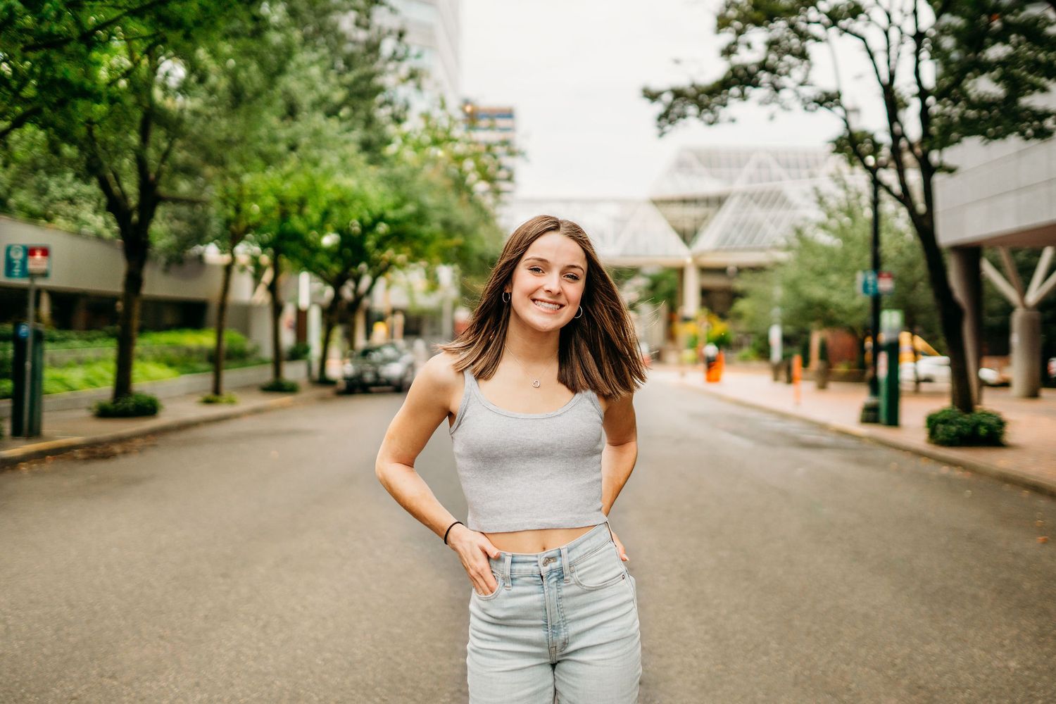 Senior girl standing in an urban street setting, smiling confidently in Portland Oregon.
