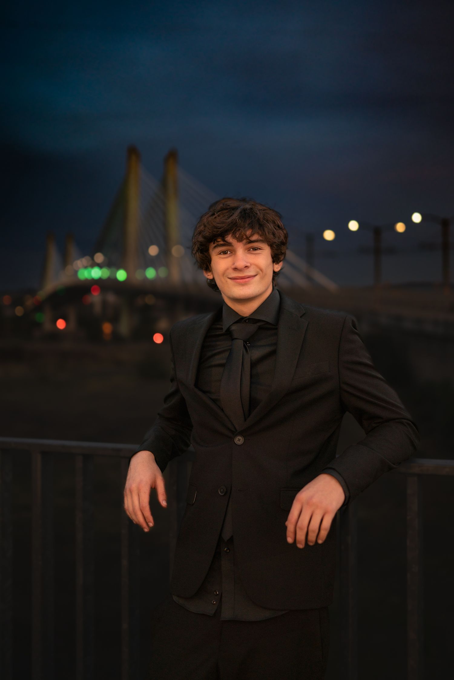 Senior boy night portrait in Portland, Oregon, with the Tillicum Bridge behind him