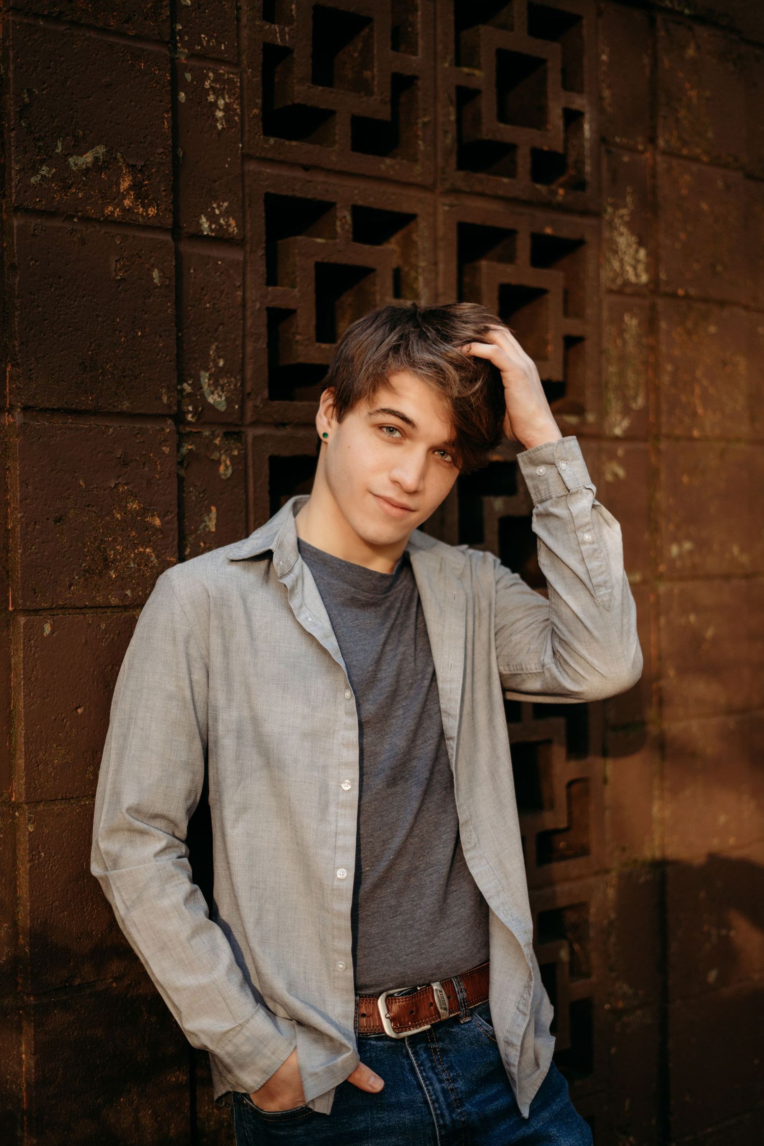 Senior boy standing against a textured wall with relaxed expression