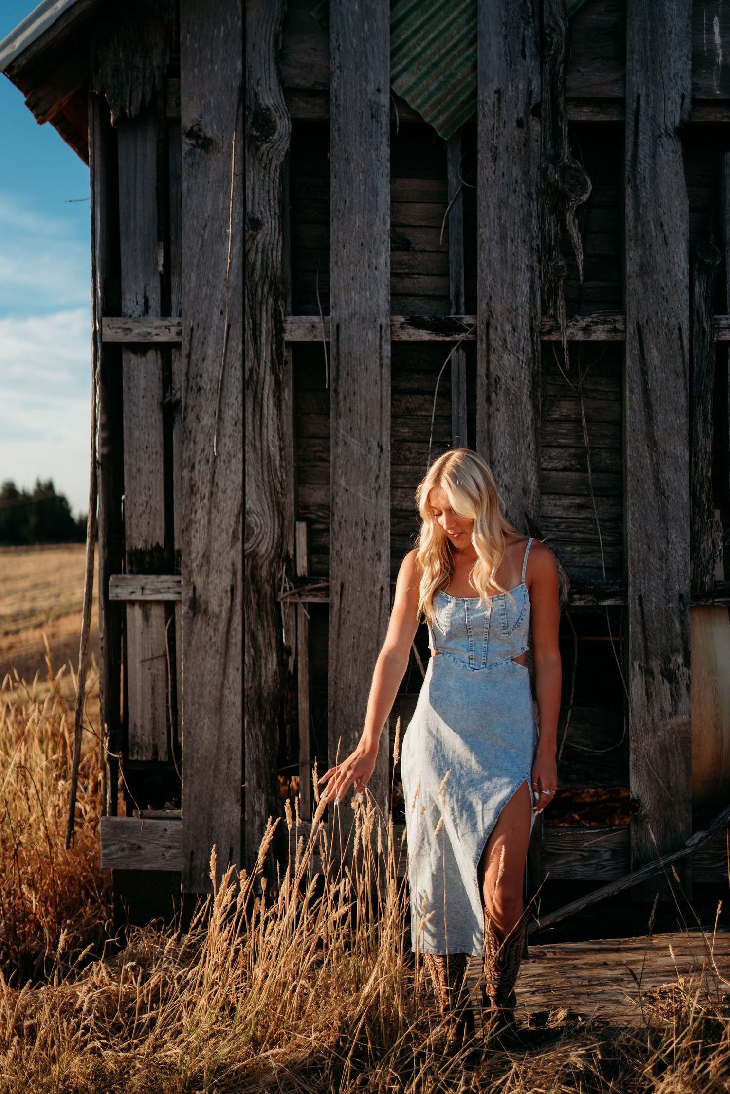 Senior girl standing in front of barn at golden hour
