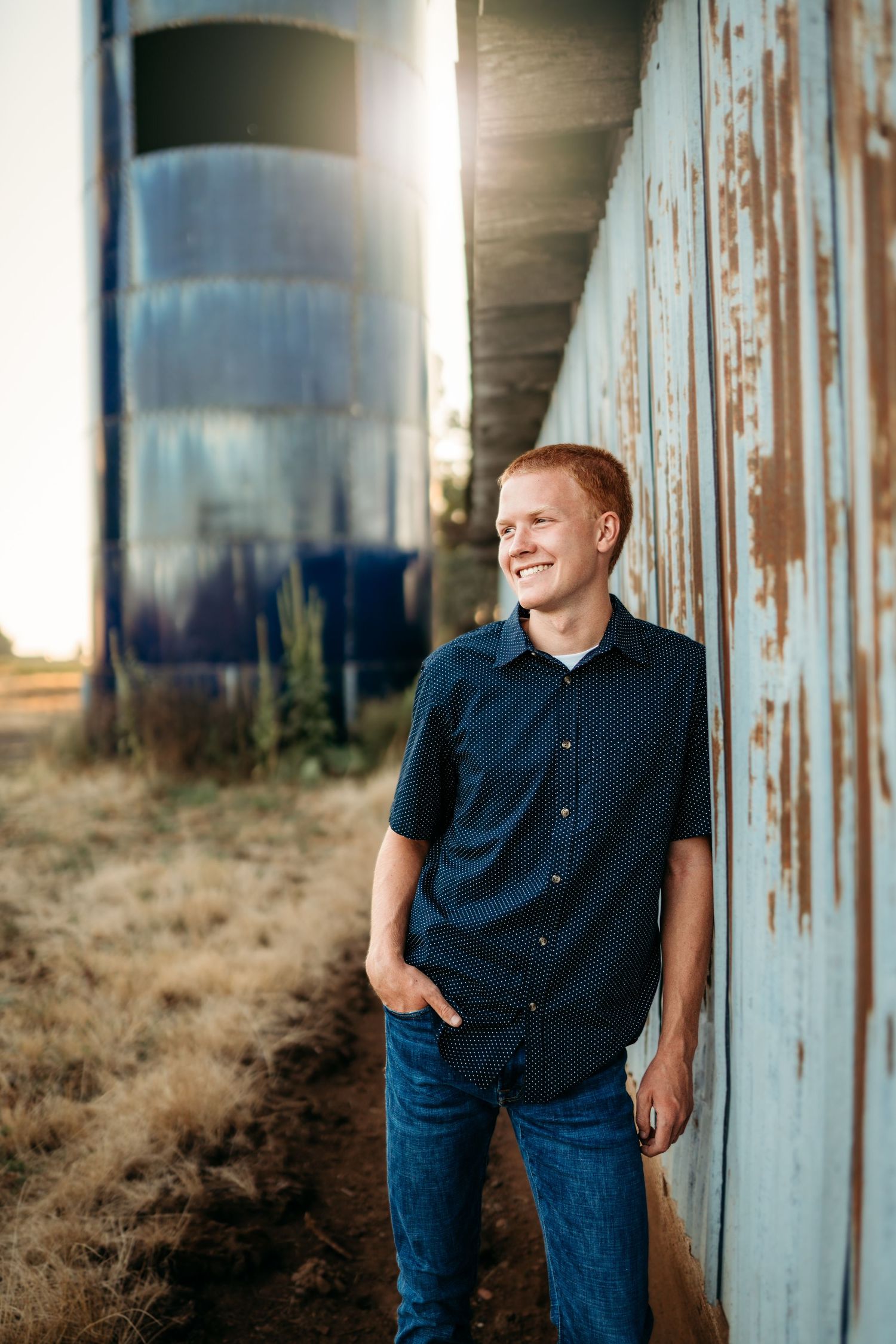Senior boy standing beside an industrial building with relaxed smile