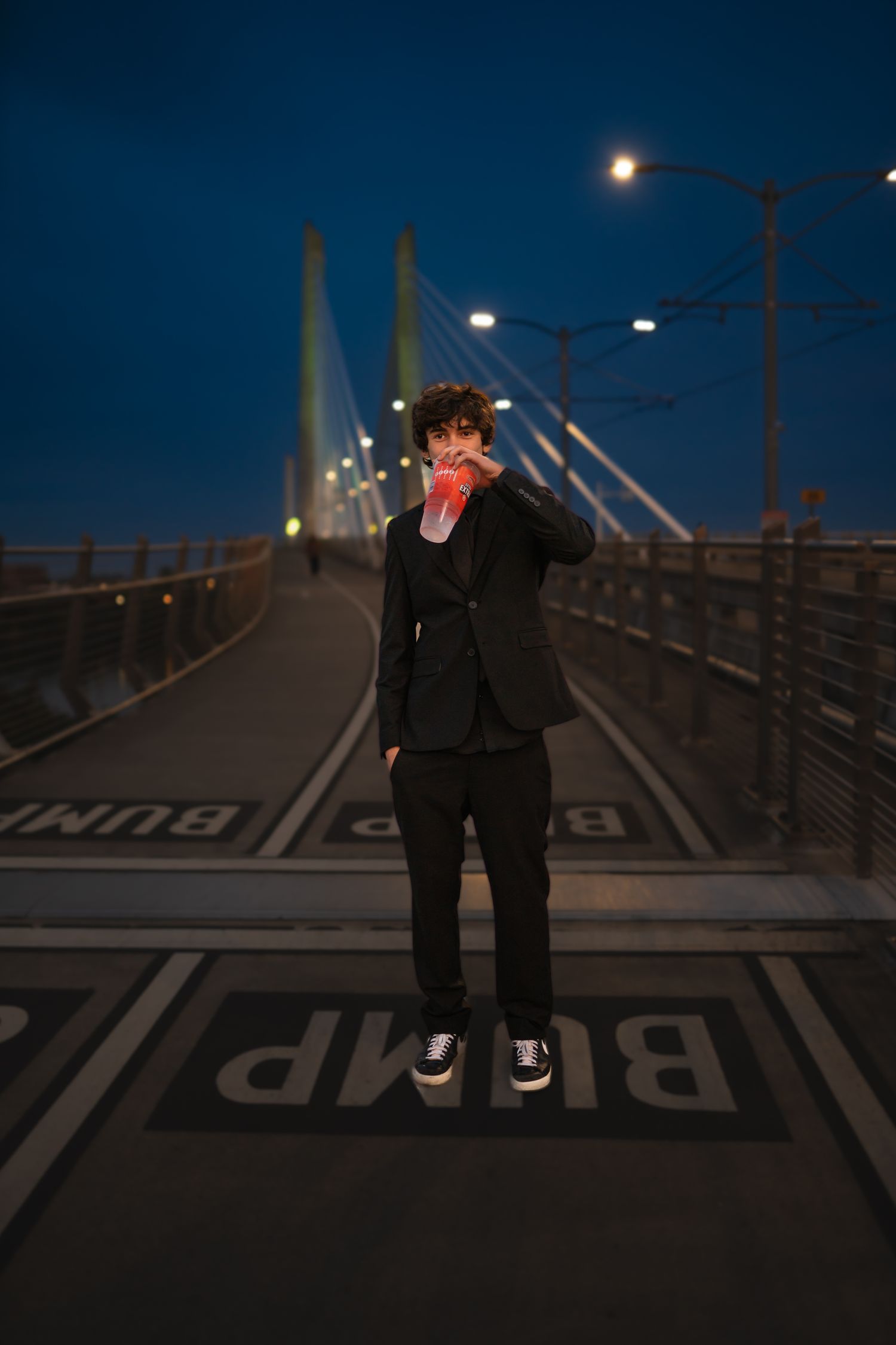 Boys standing on bridge drinking a soda