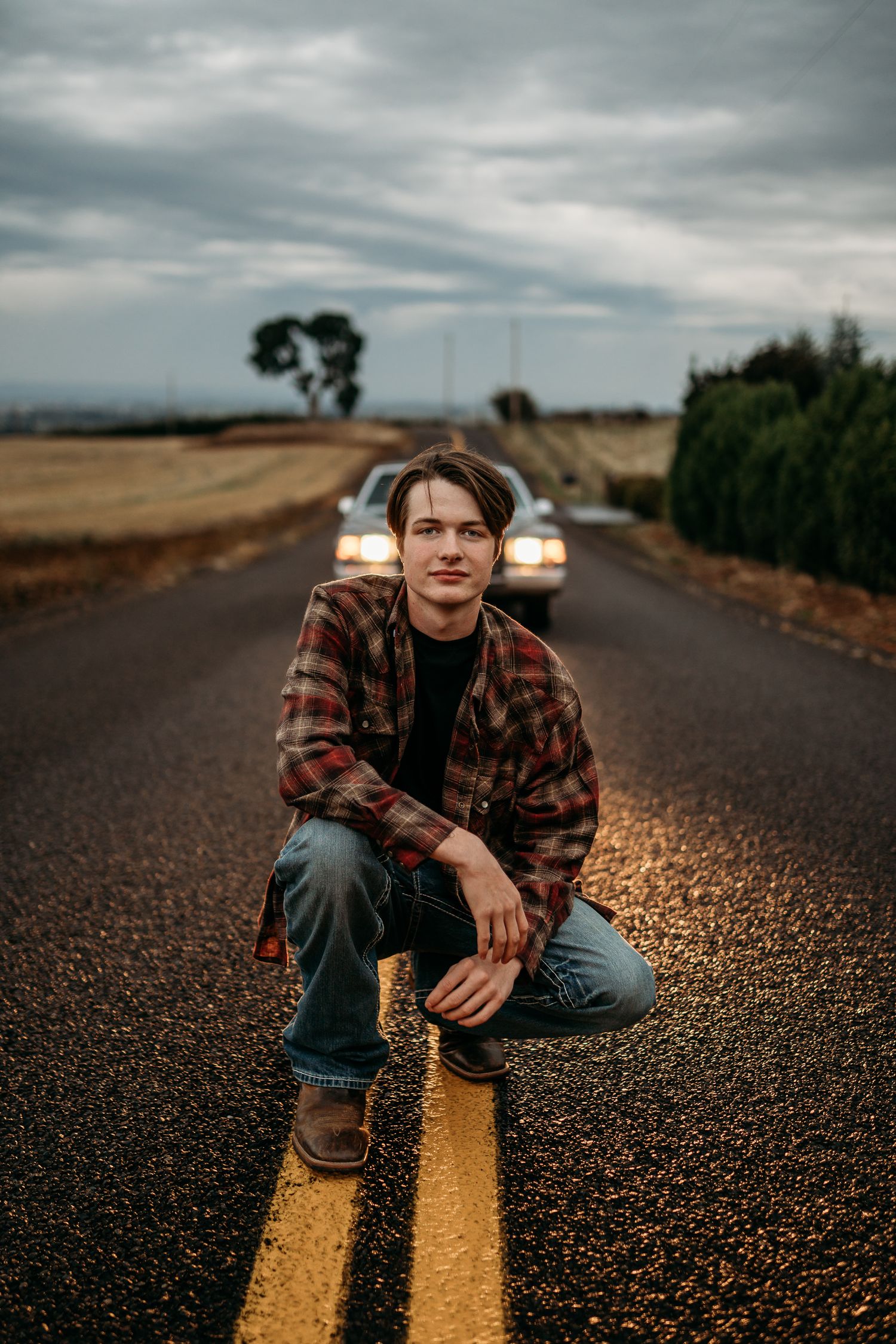 Senior boy crouching in the road with relaxed, confident expression