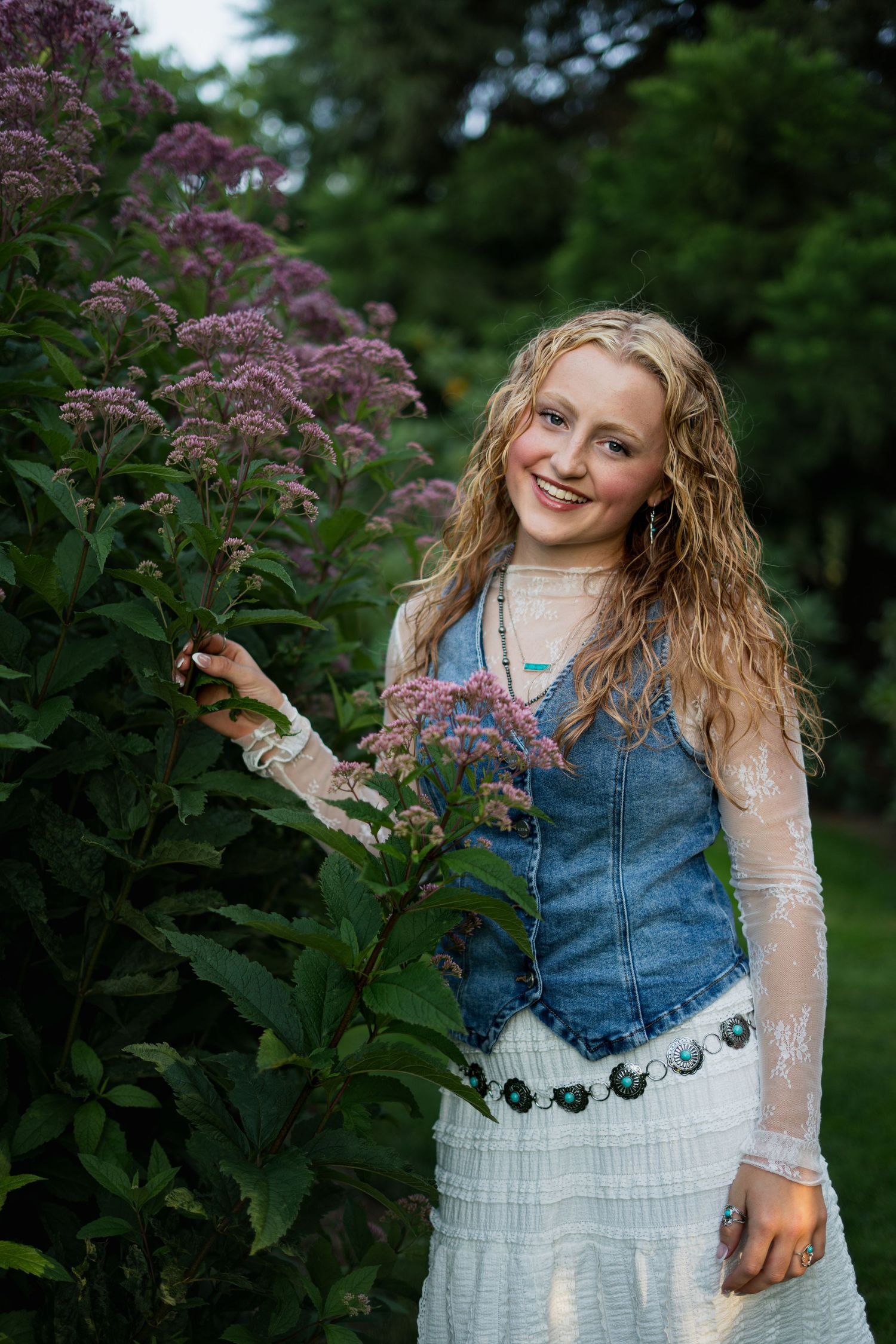 Senior girl standing next to flowers smiling confidently