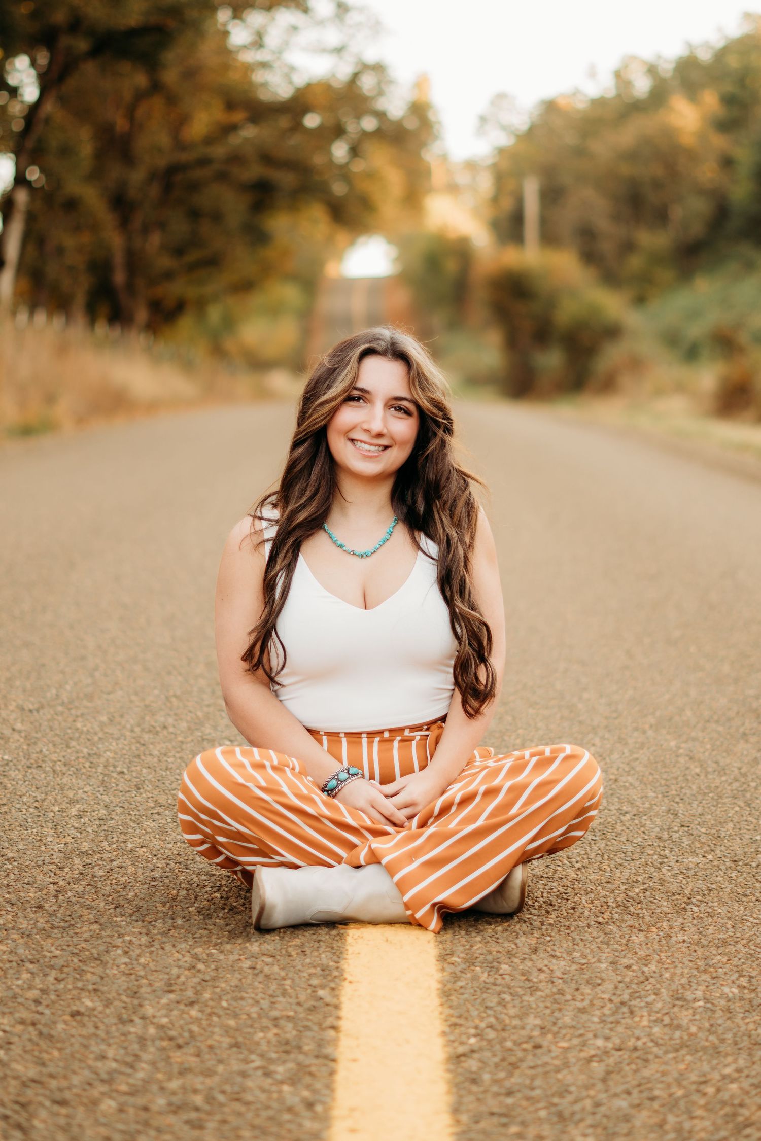 Confident senior girl sitting in the road and smiling