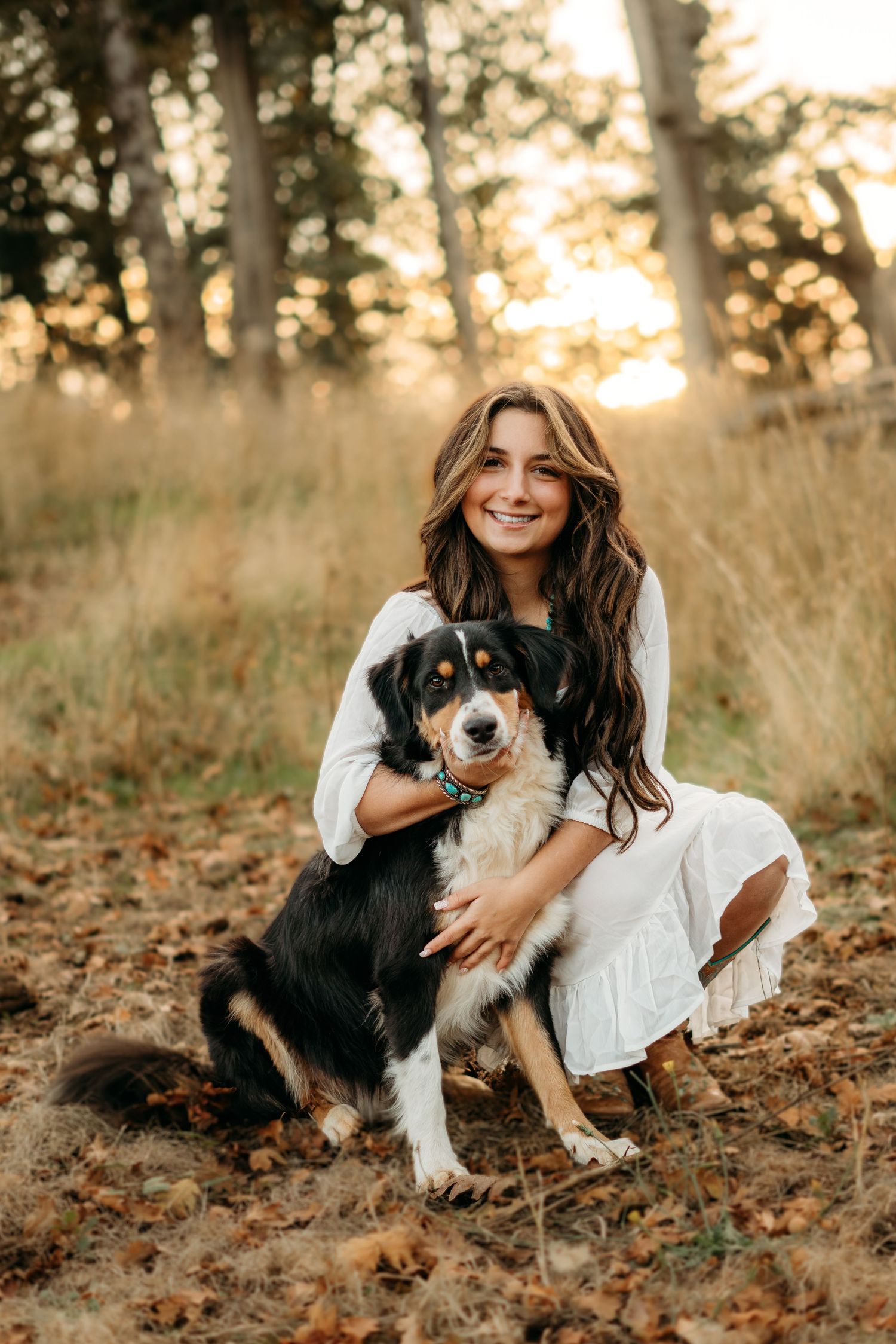 Senior girl sitting in the woods holding her dog during an outdoor session