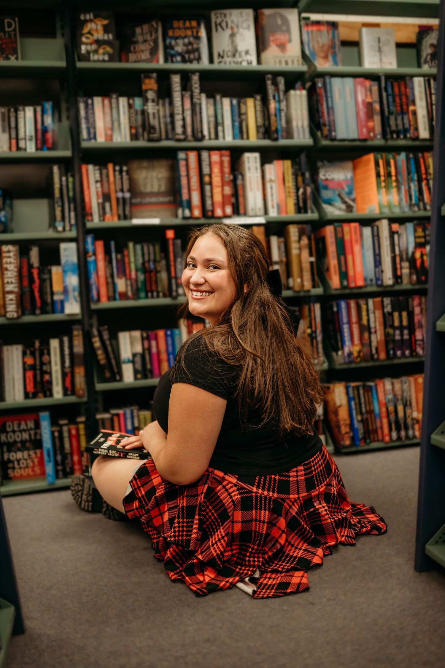 Senior girl sitting in a bookstore smiling naturally