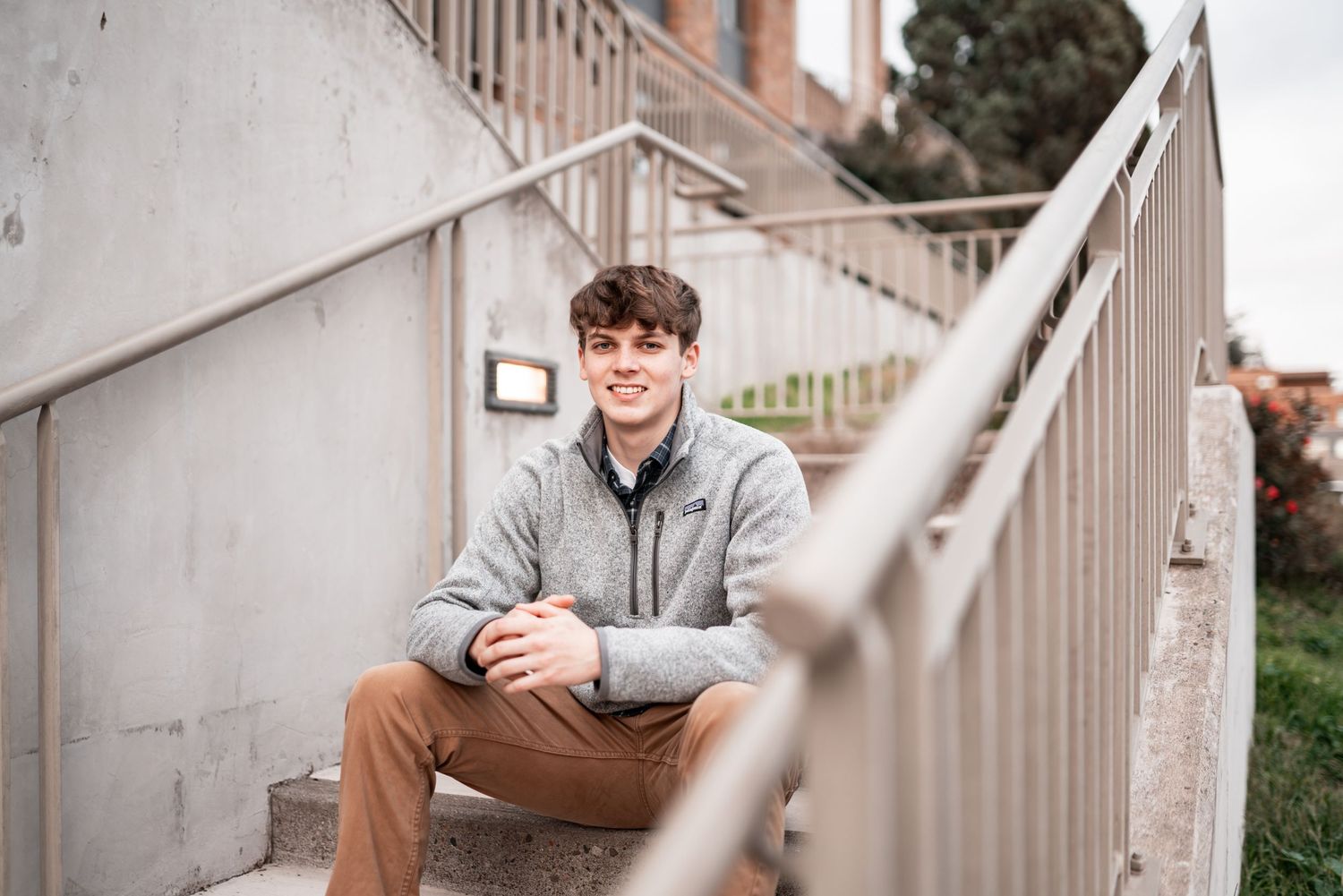 Senior boy sitting on outdoor stairs with relaxed smile