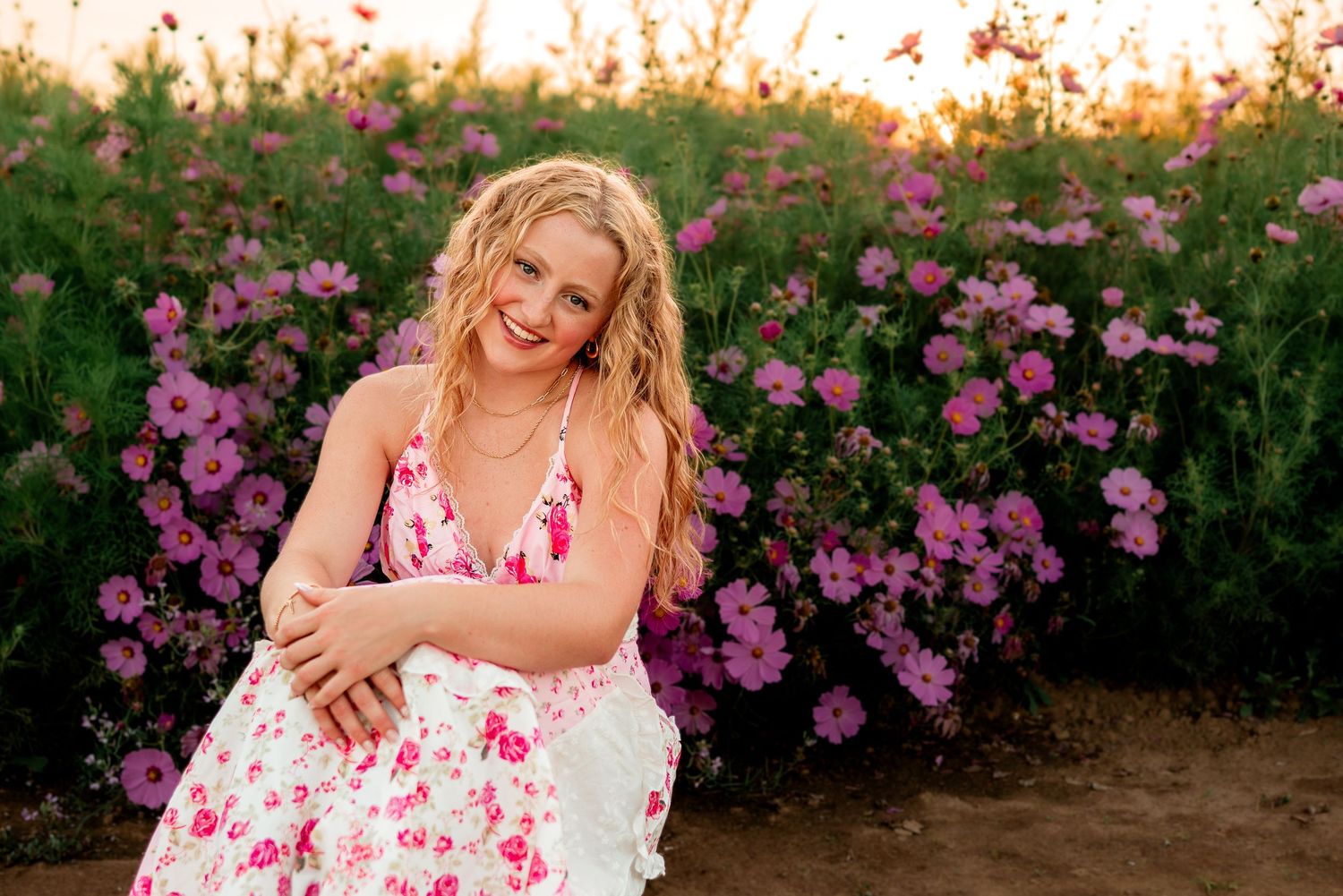 Senior girl sitting in a flower garden wearing a pink dress
