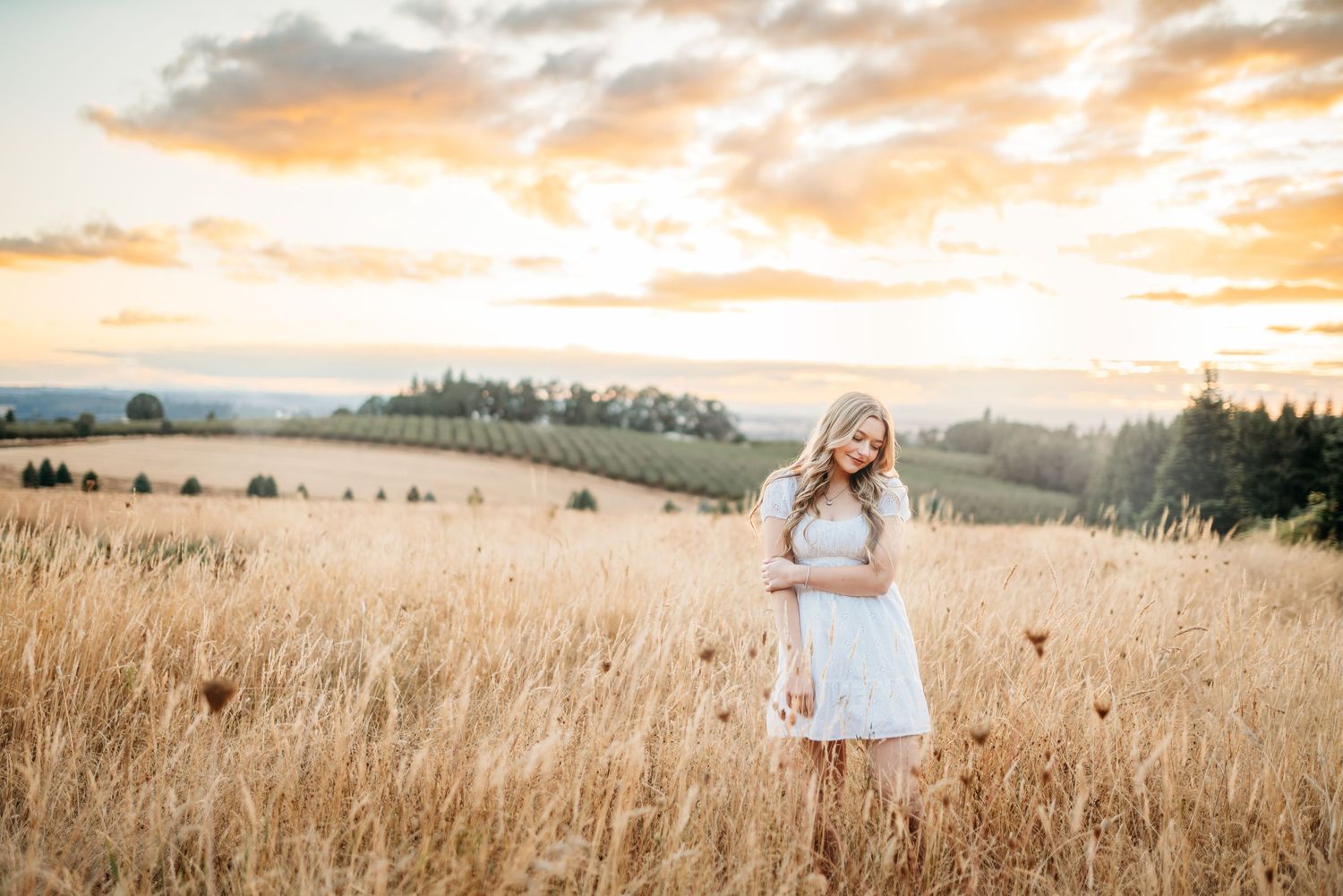 Senior high school portrait of girl standing in field at sunset