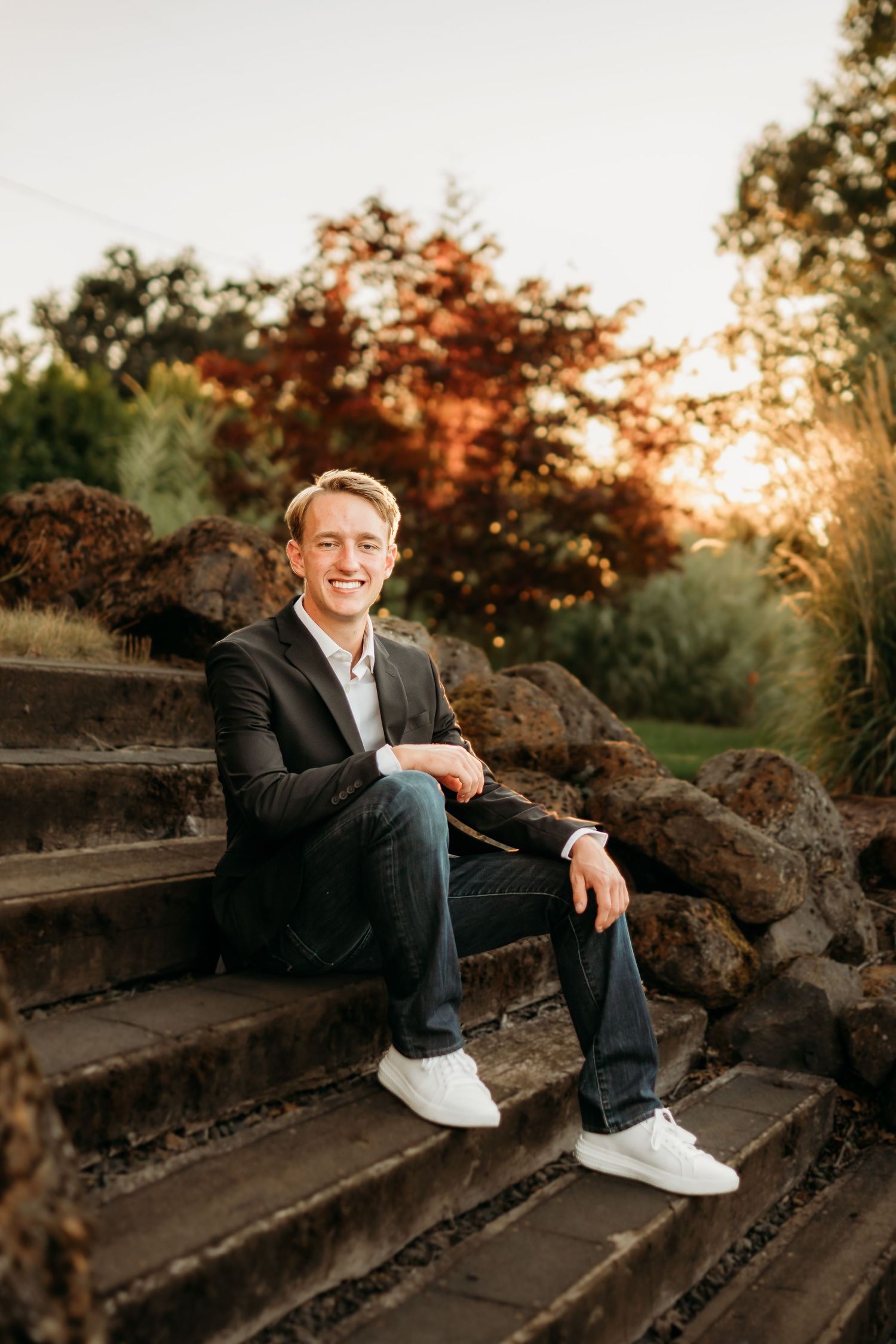 Relaxed senior boy sitting on steps and smiling at sunset