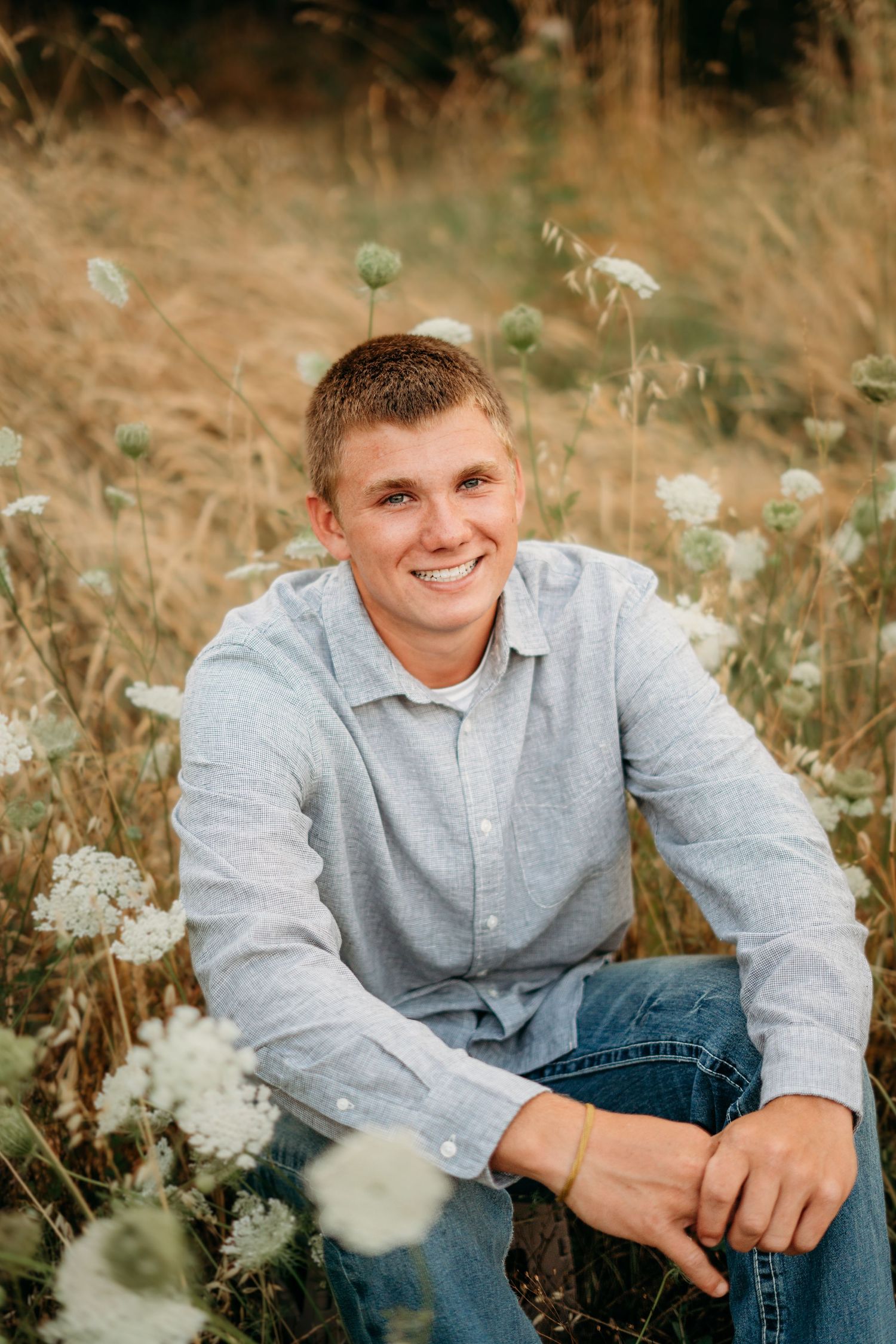 Senior boy sitting in a field with a natural, relaxed smile
