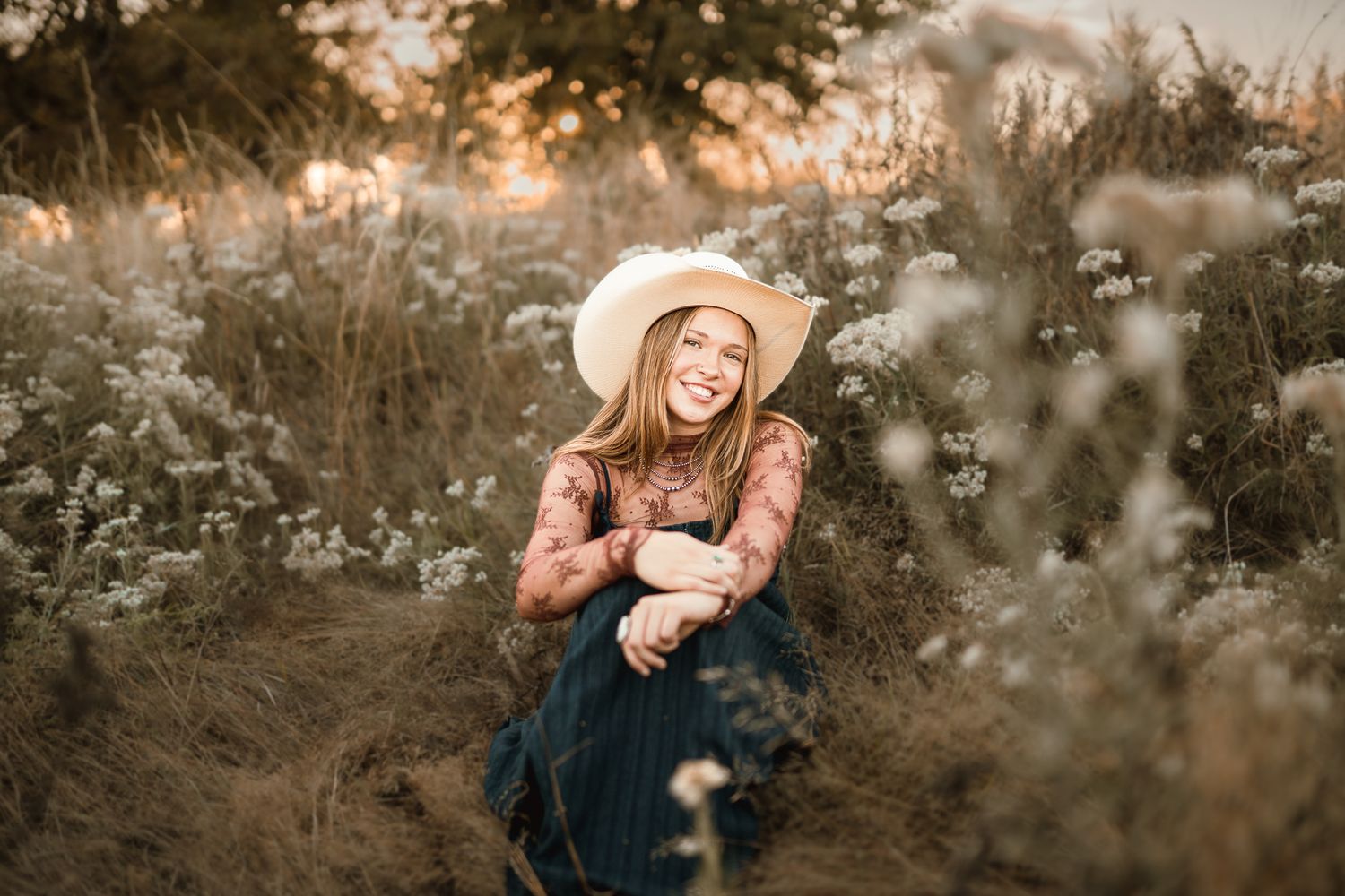 Senior girl sitting smiling and relaxed surrounded by flowers