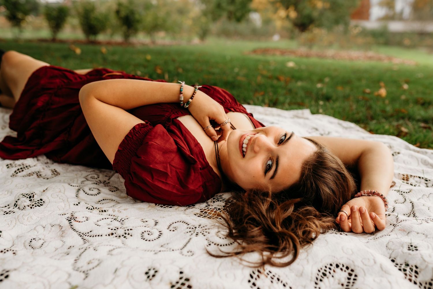 Senior girl laying on a blanket in the grass smiling.