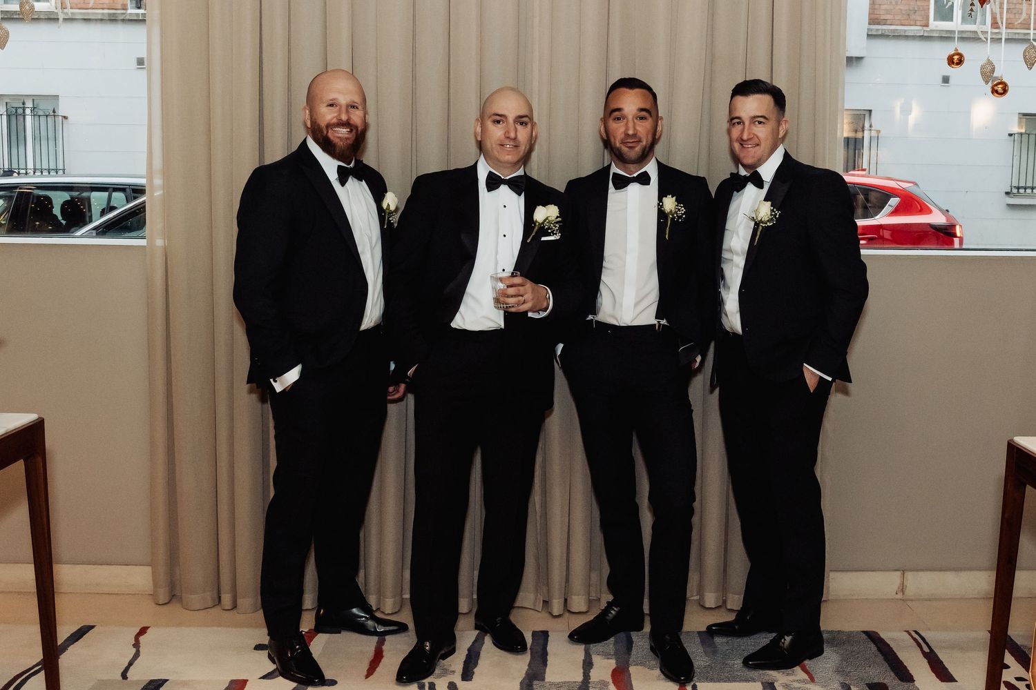 Groomsmen in black tuxedos lined up for formal wedding party photo.