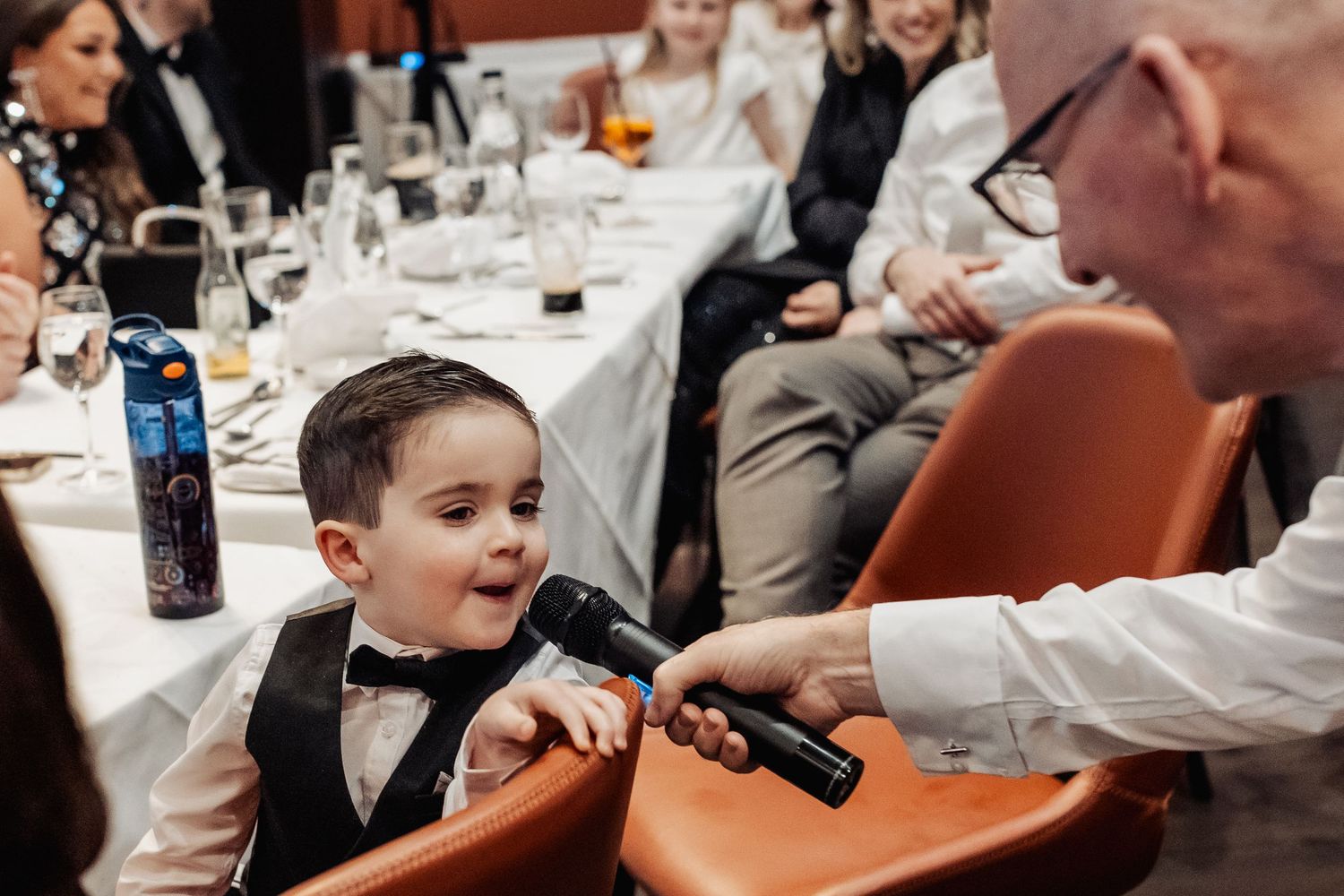 Wedding guests seated at decorated tables during reception dinner service.
