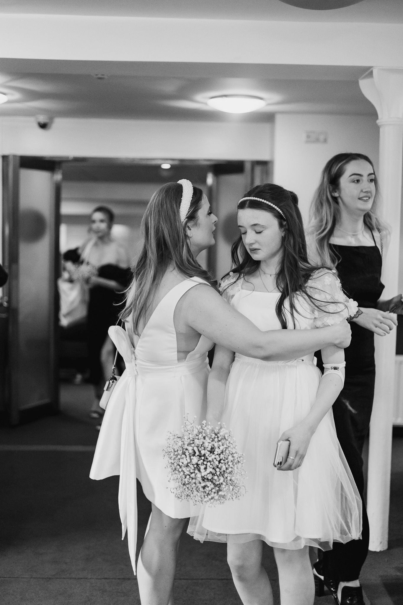 Young attendants in white dresses carry baby's breath bouquets in Dublin reg office.