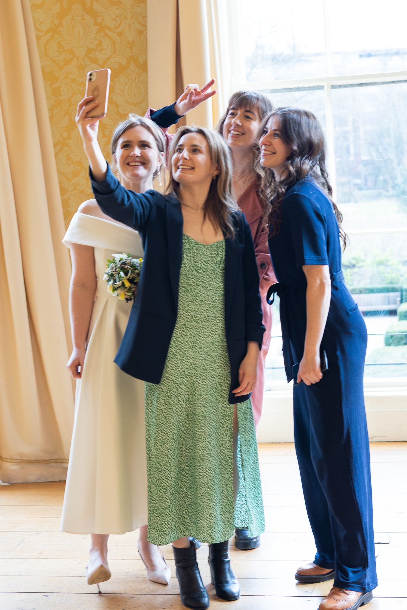 A group of wedding guests taking a selfie together by a sunny window in MoLI during Dublin city wedding.