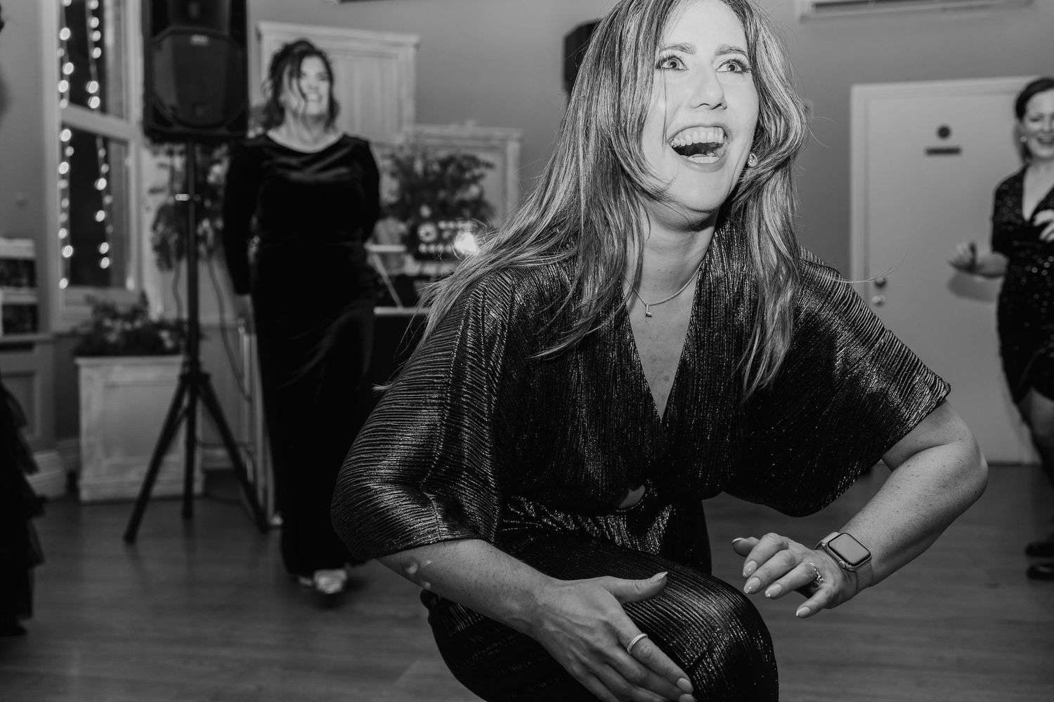 Woman dancing joyfully at a party in black and white photography at an indoor event.