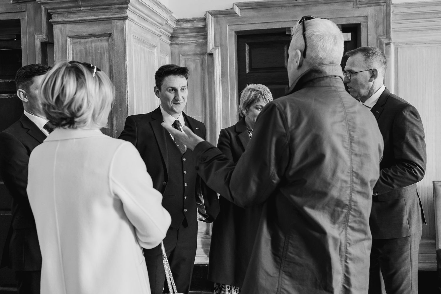 A black and white photo of people gathered in conversation in MoLI hallway During Dublin City wedding.