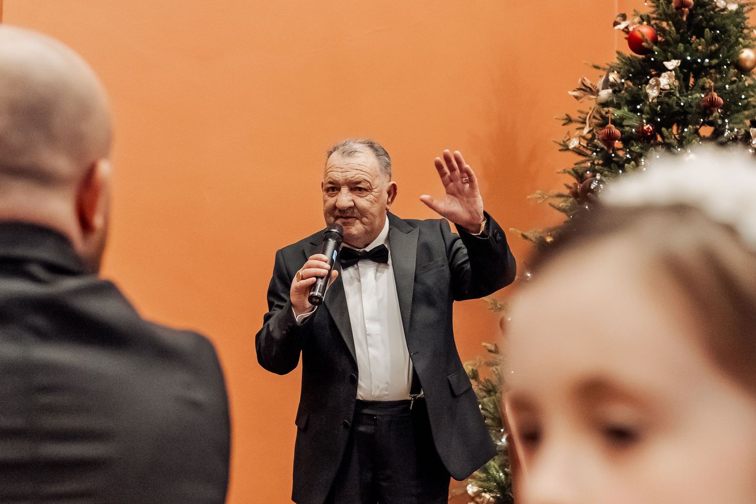 Wedding reception speech with decorated Christmas tree in background.