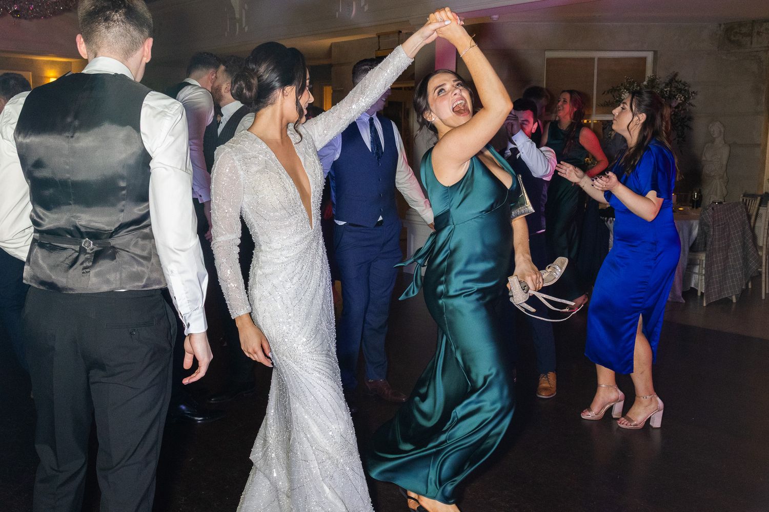 Wedding guests dancing and twirling on the dance floor at a reception.